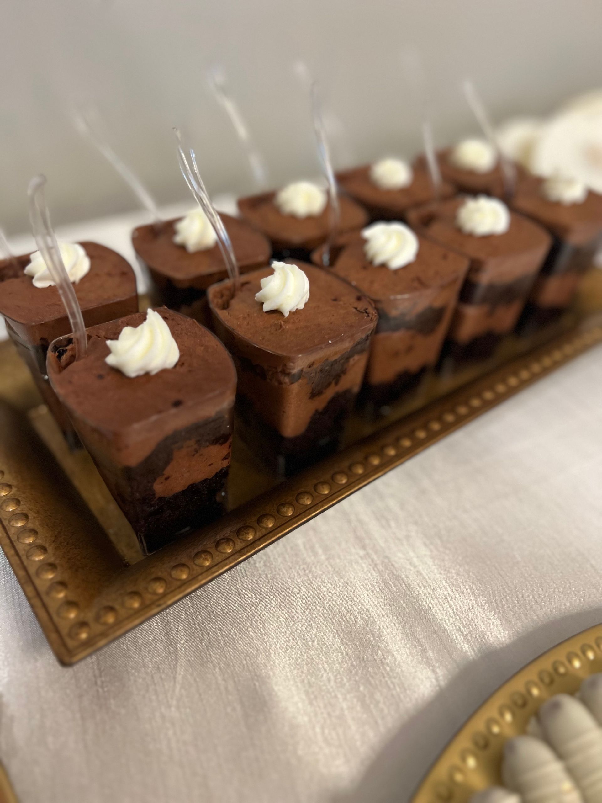 a tray of chocolate desserts with whipped cream on top on a table .
