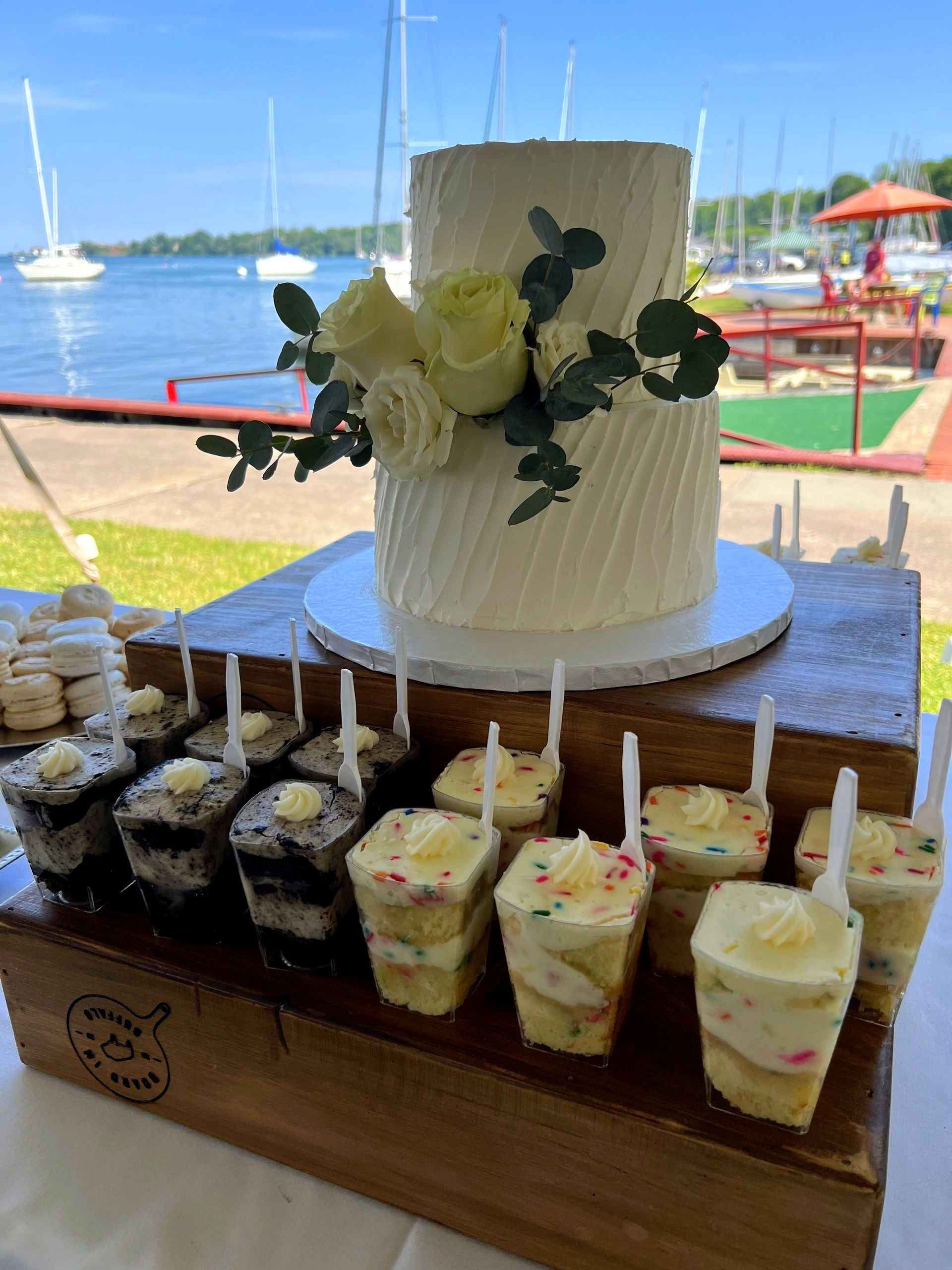 a wedding cake is sitting on top of a wooden table next to cupcakes .