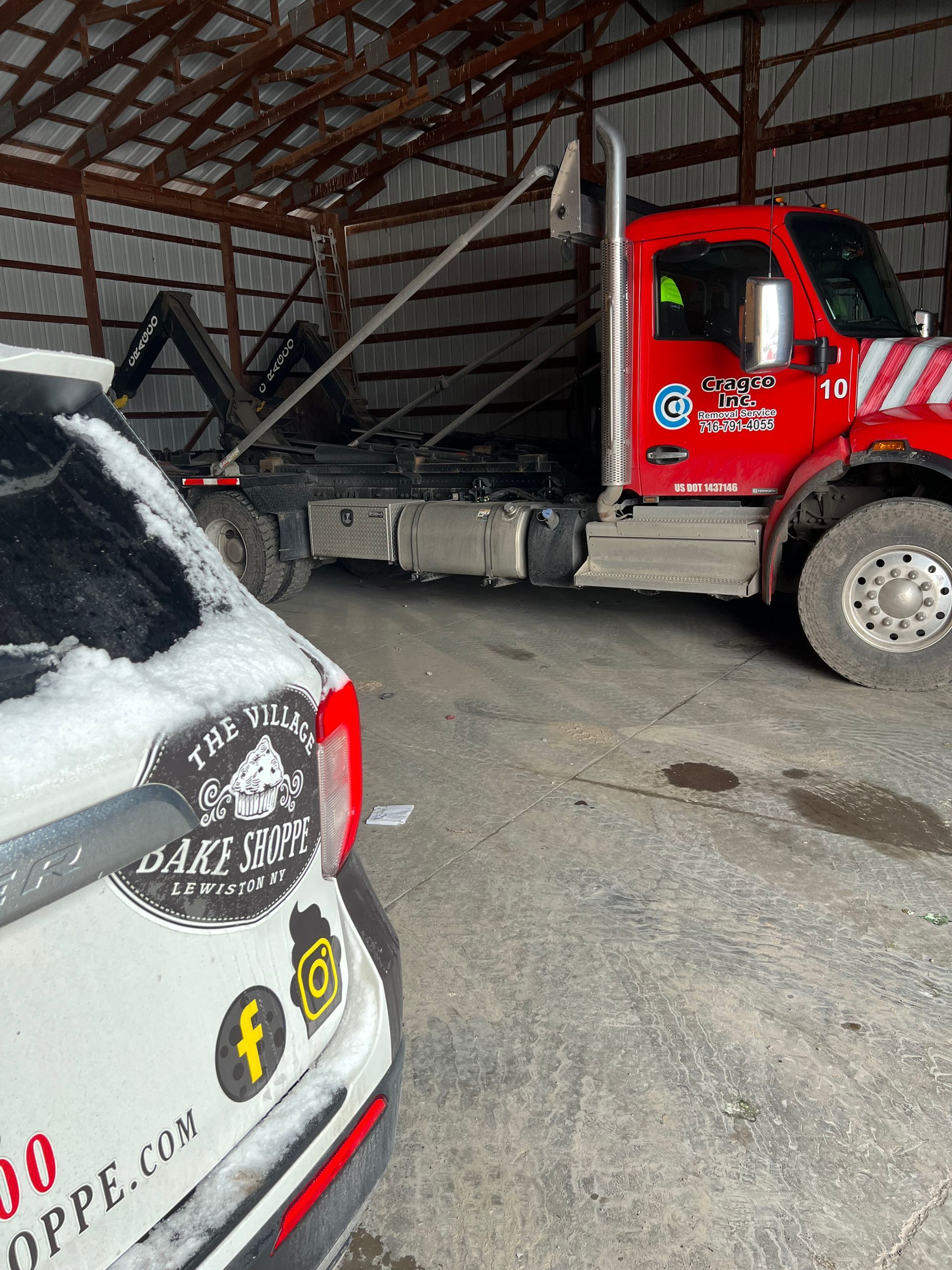 a red tow truck is parked in a garage next to a white car .