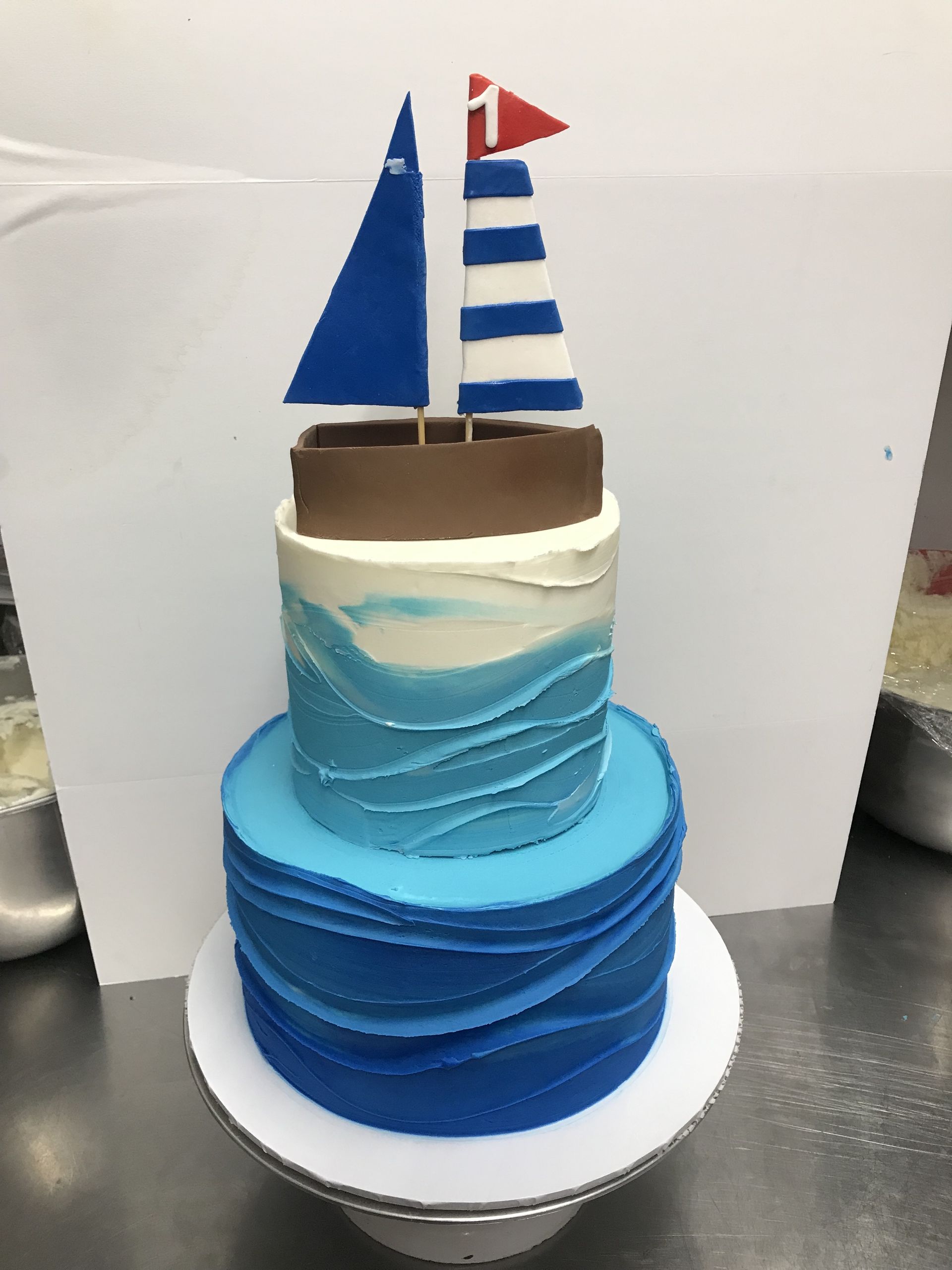a blue and white cake with a sailboat on top of it .