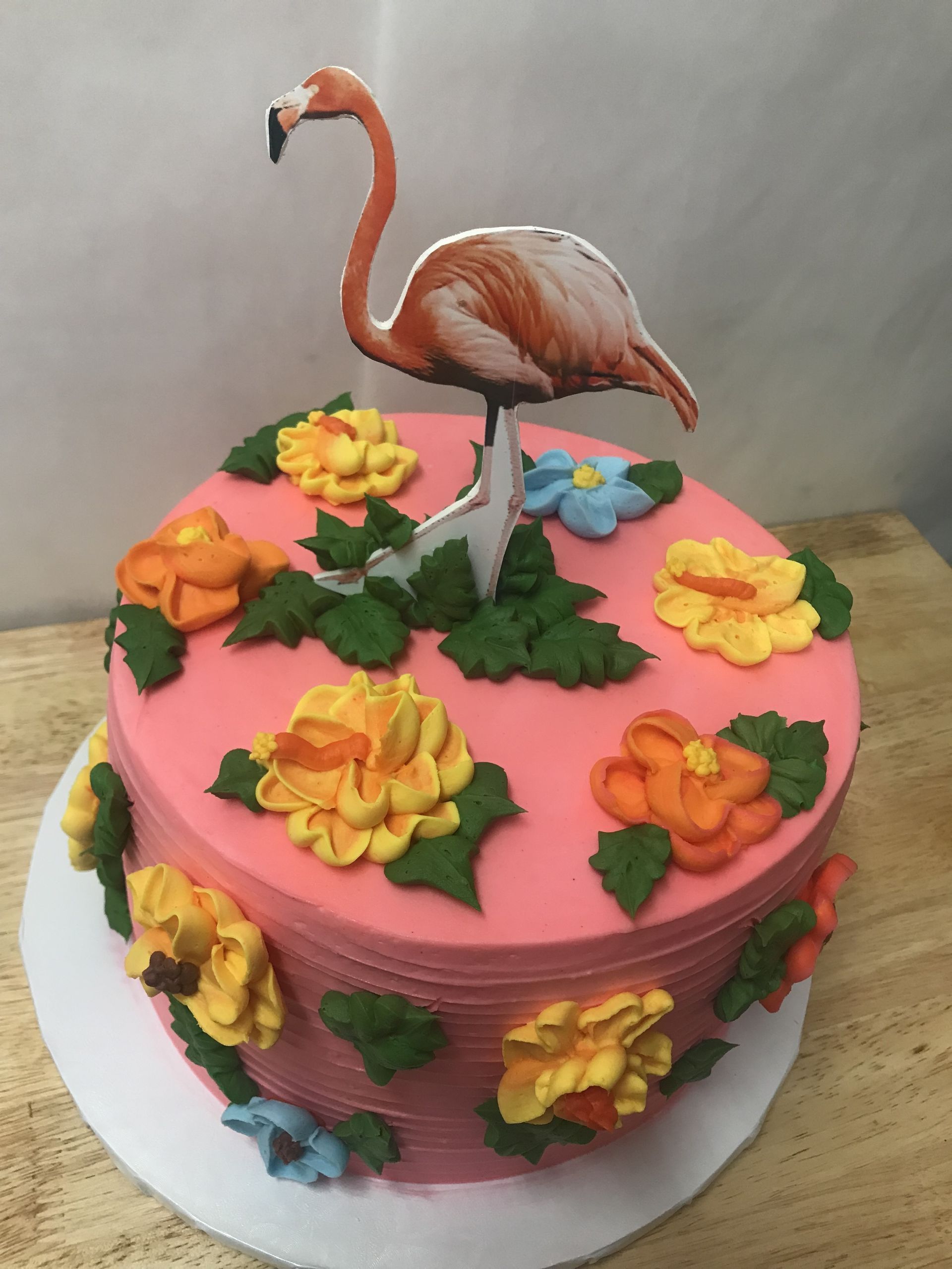 a pink cake with flowers and a flamingo on top