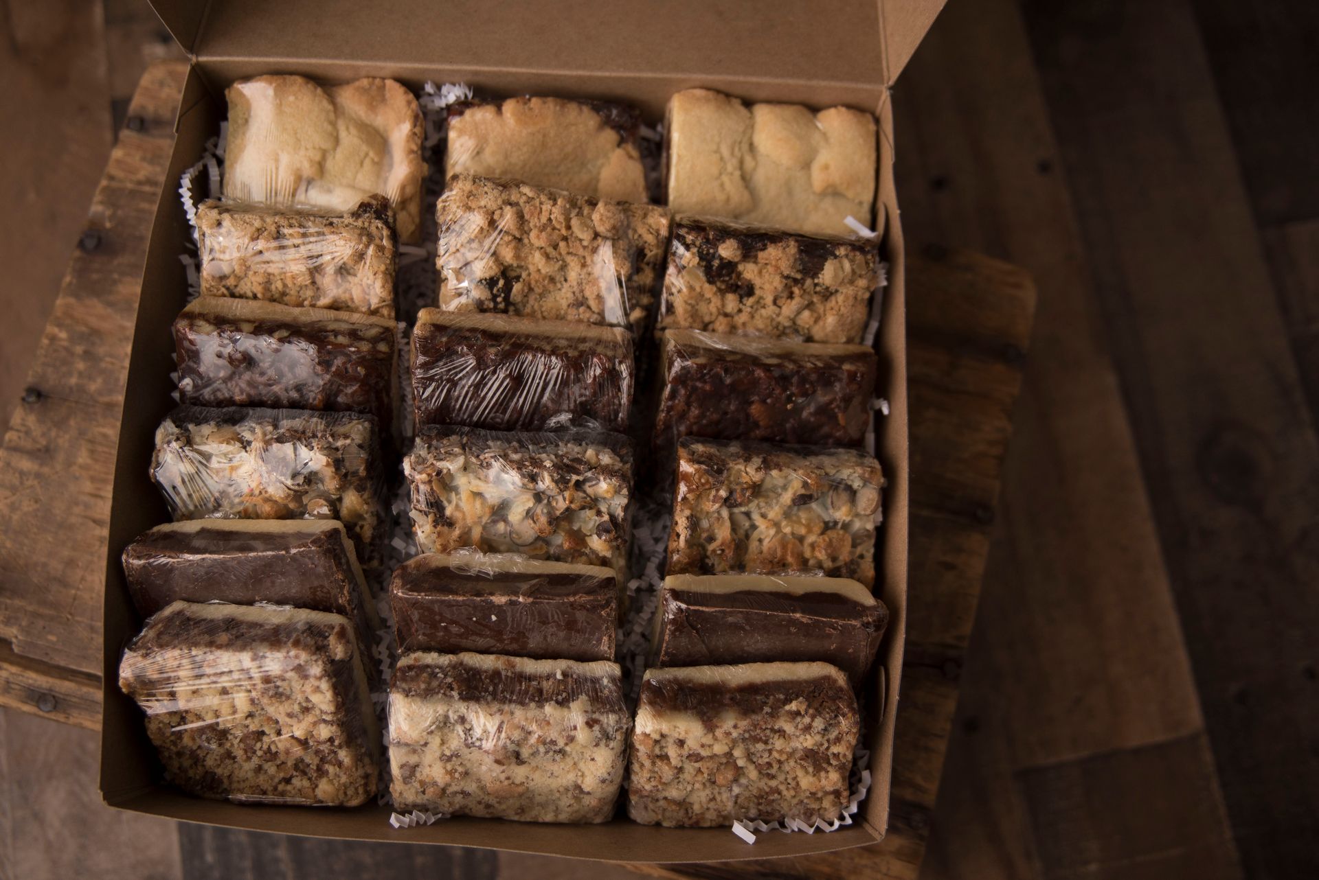 a box filled with a variety of desserts is sitting on a wooden table .