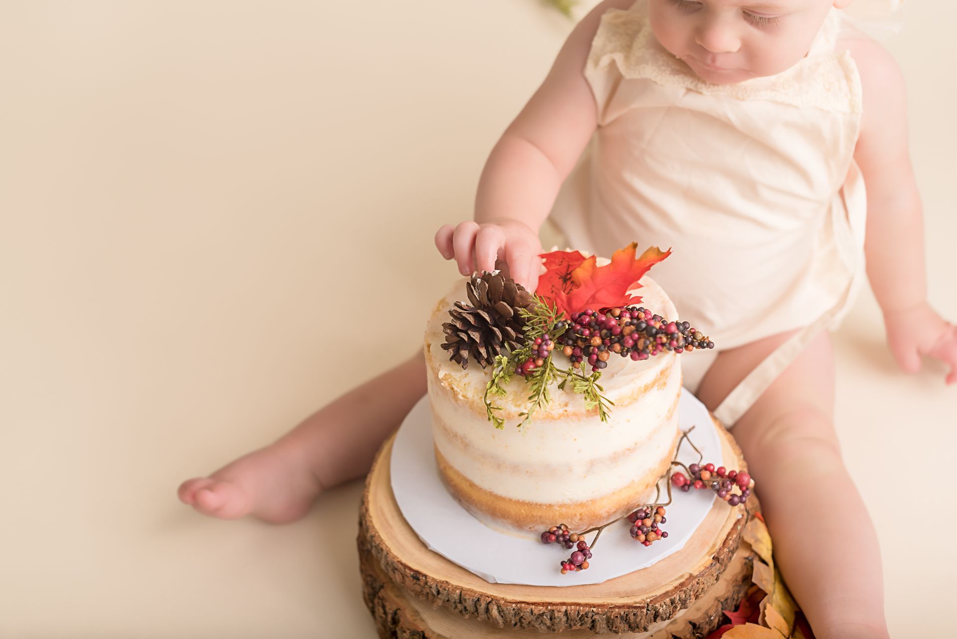 a baby is sitting on a wooden stump eating a cake .