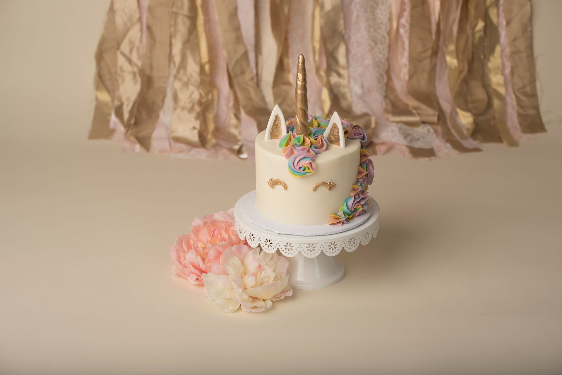 a unicorn cake is sitting on top of a white cake stand .