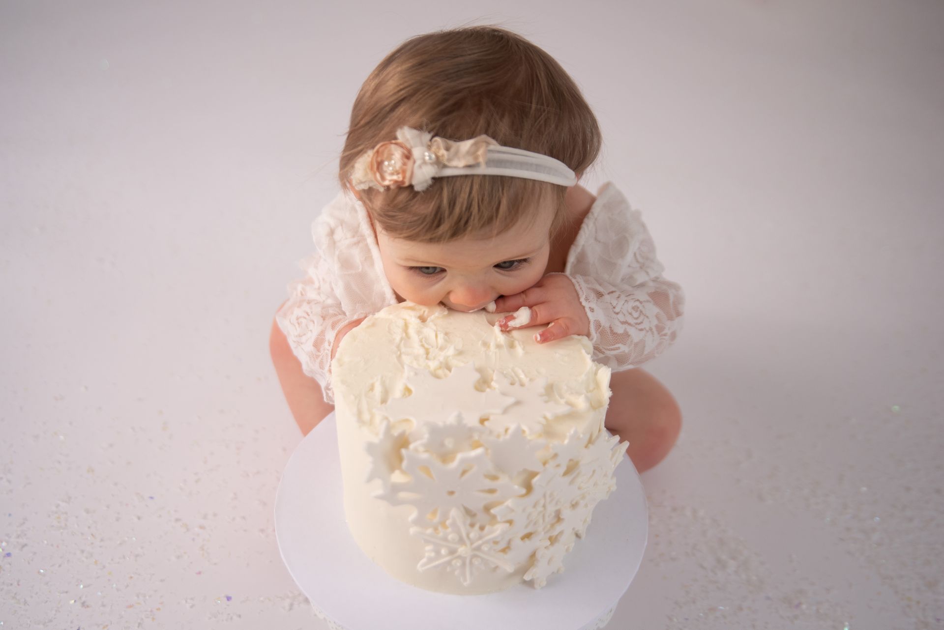 a baby girl is eating a piece of cake .