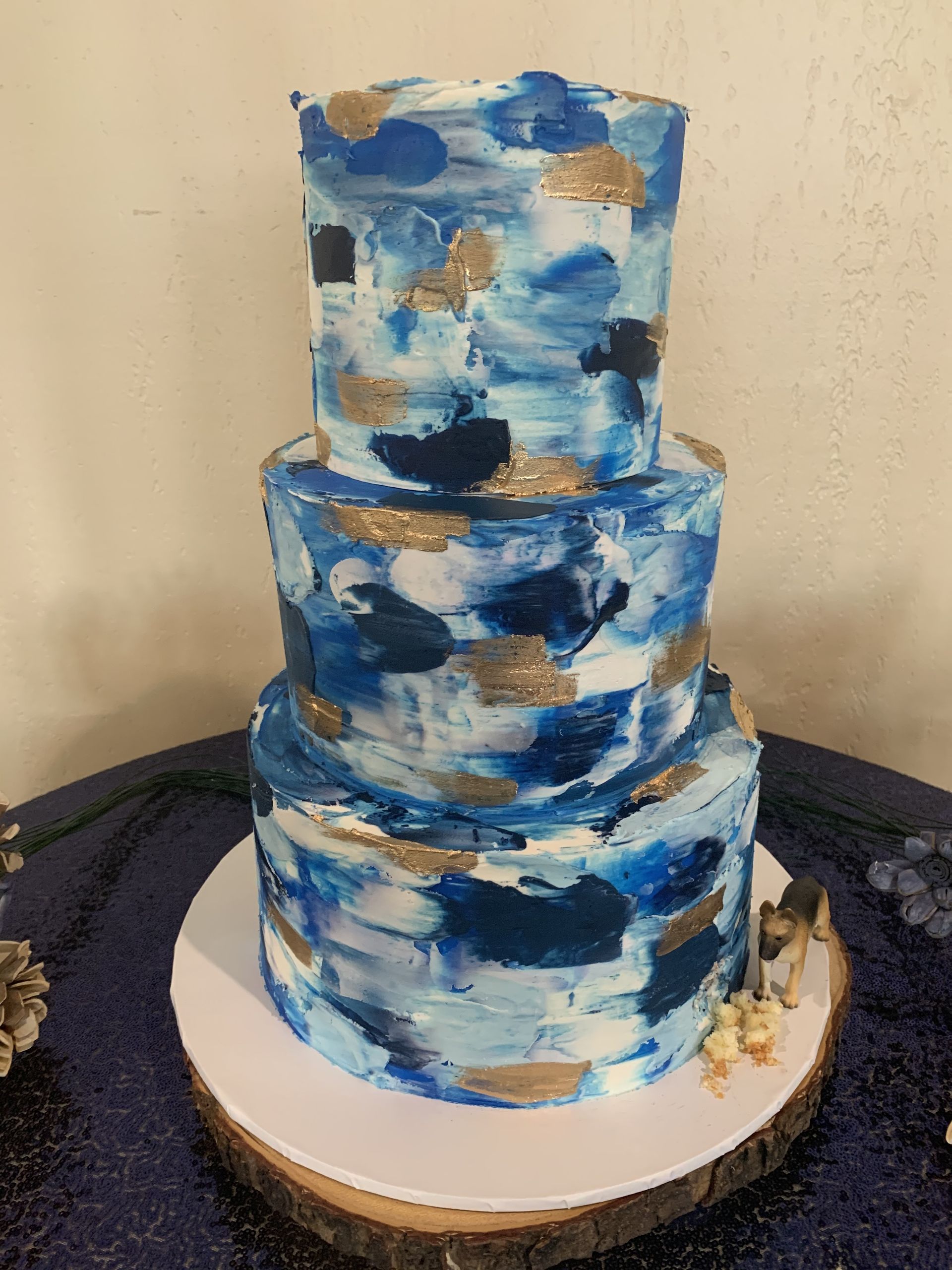 a blue and gold cake is sitting on top of a wooden table .