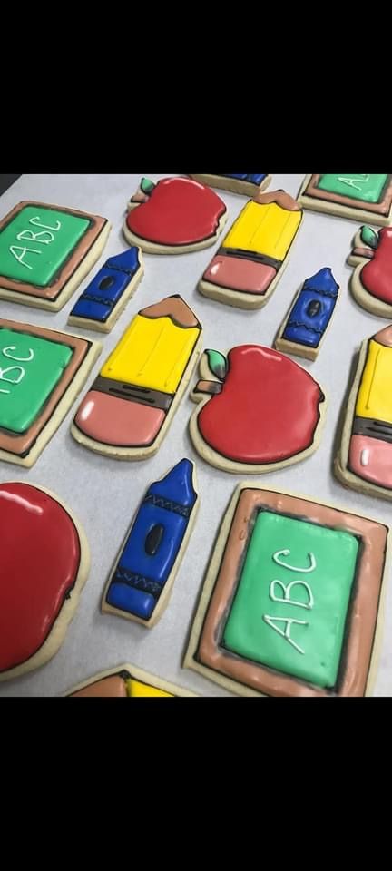 a bunch of cookies decorated to look like school supplies are sitting on a table .