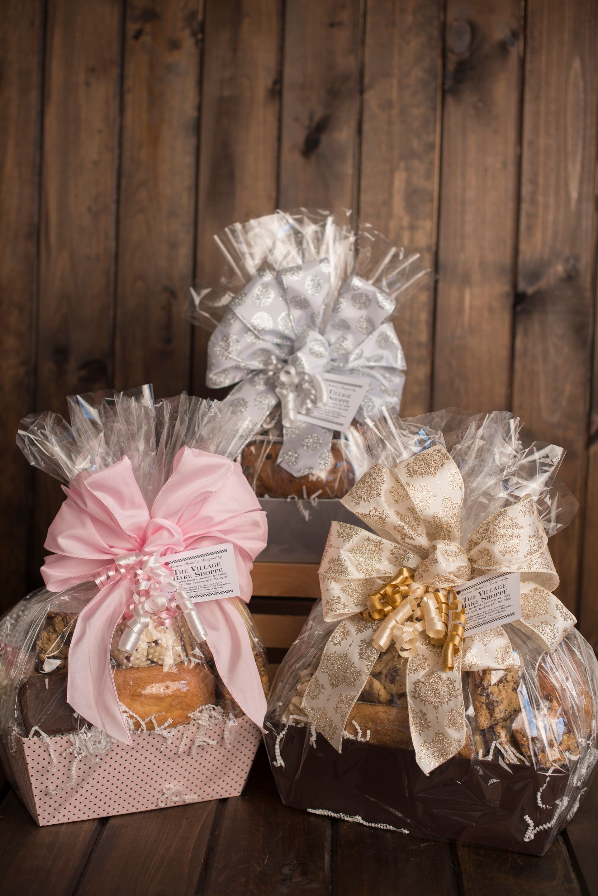 three gift baskets with bows on them are sitting on a wooden table .