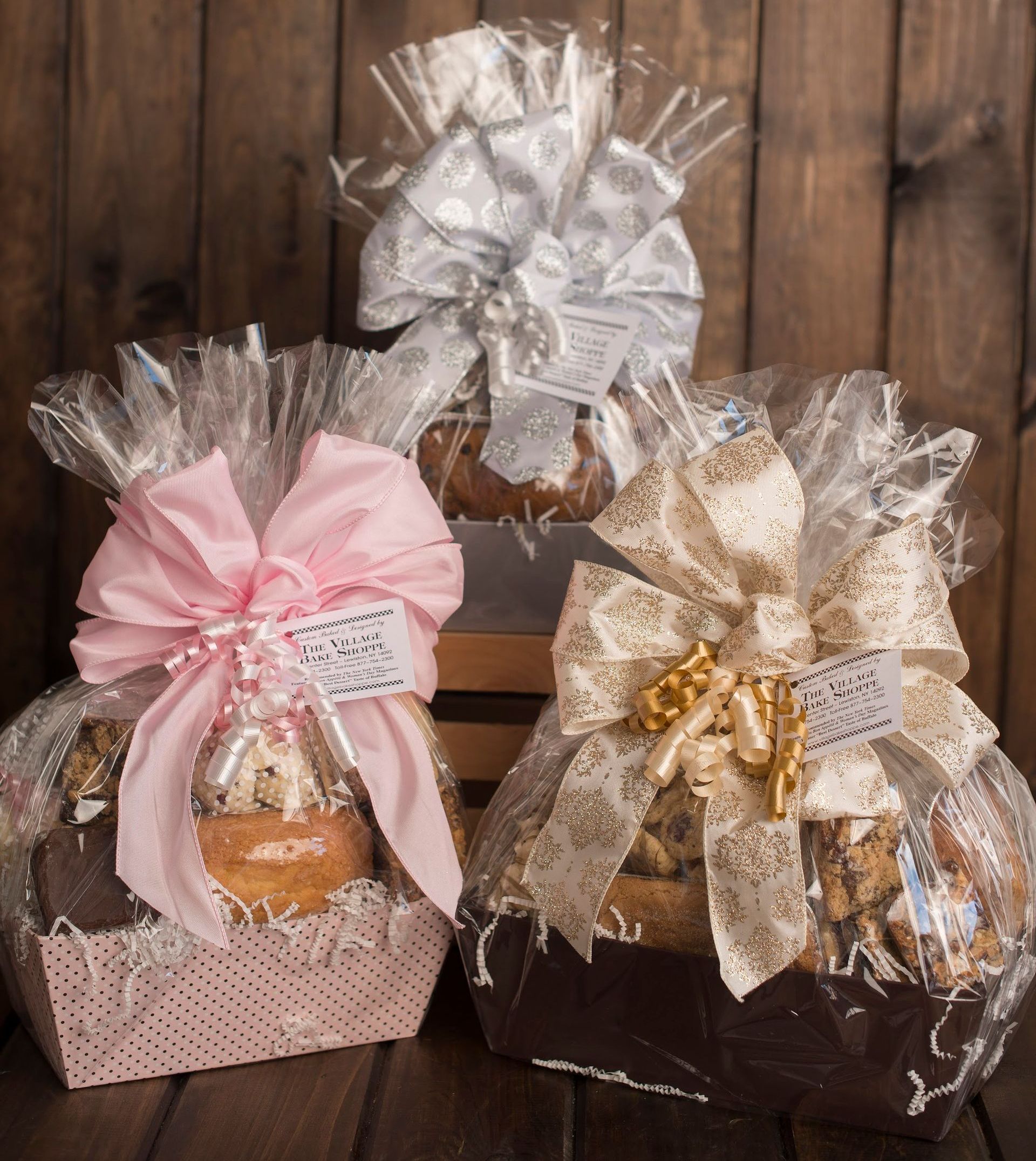 three gift baskets with bows on them are sitting on a wooden table .