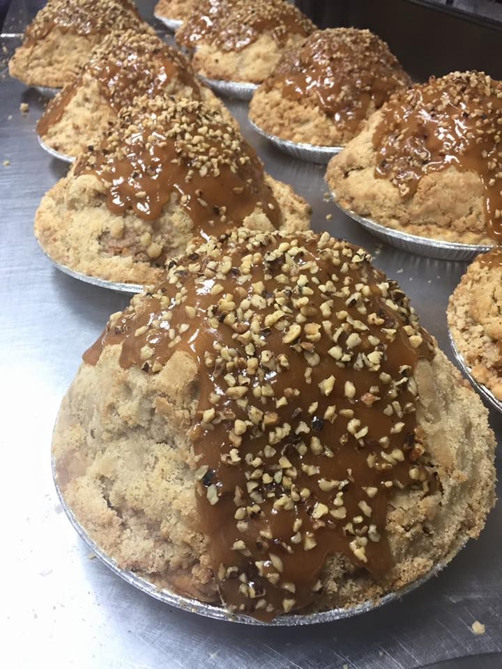 a row of apple pie with caramel sauce and nuts on top .