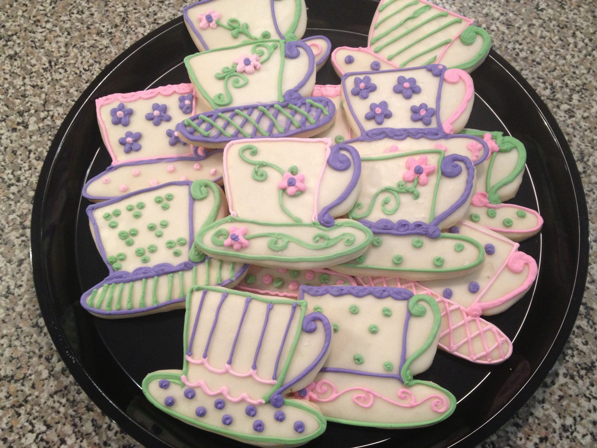 a plate of decorated cookies in the shape of tea cups and saucers