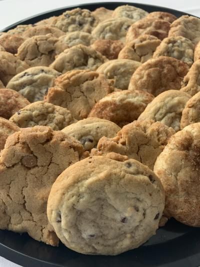 a black plate filled with chocolate chip cookies on a table .