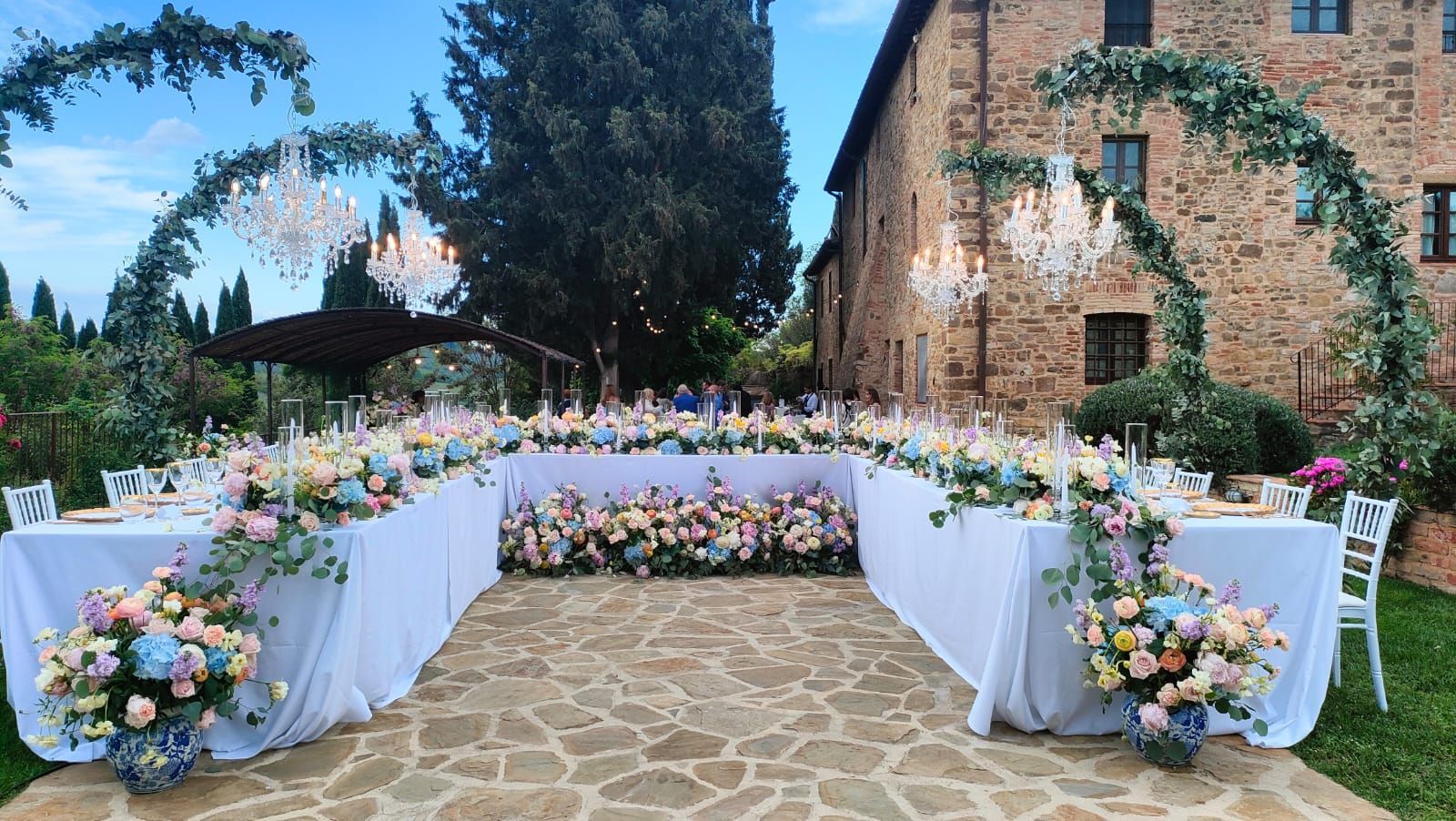 Una tavola apparecchiata con un centrotavola floreale viola e bianco, piccole ciotole bianche e pietre decorative viola sul tavolo.