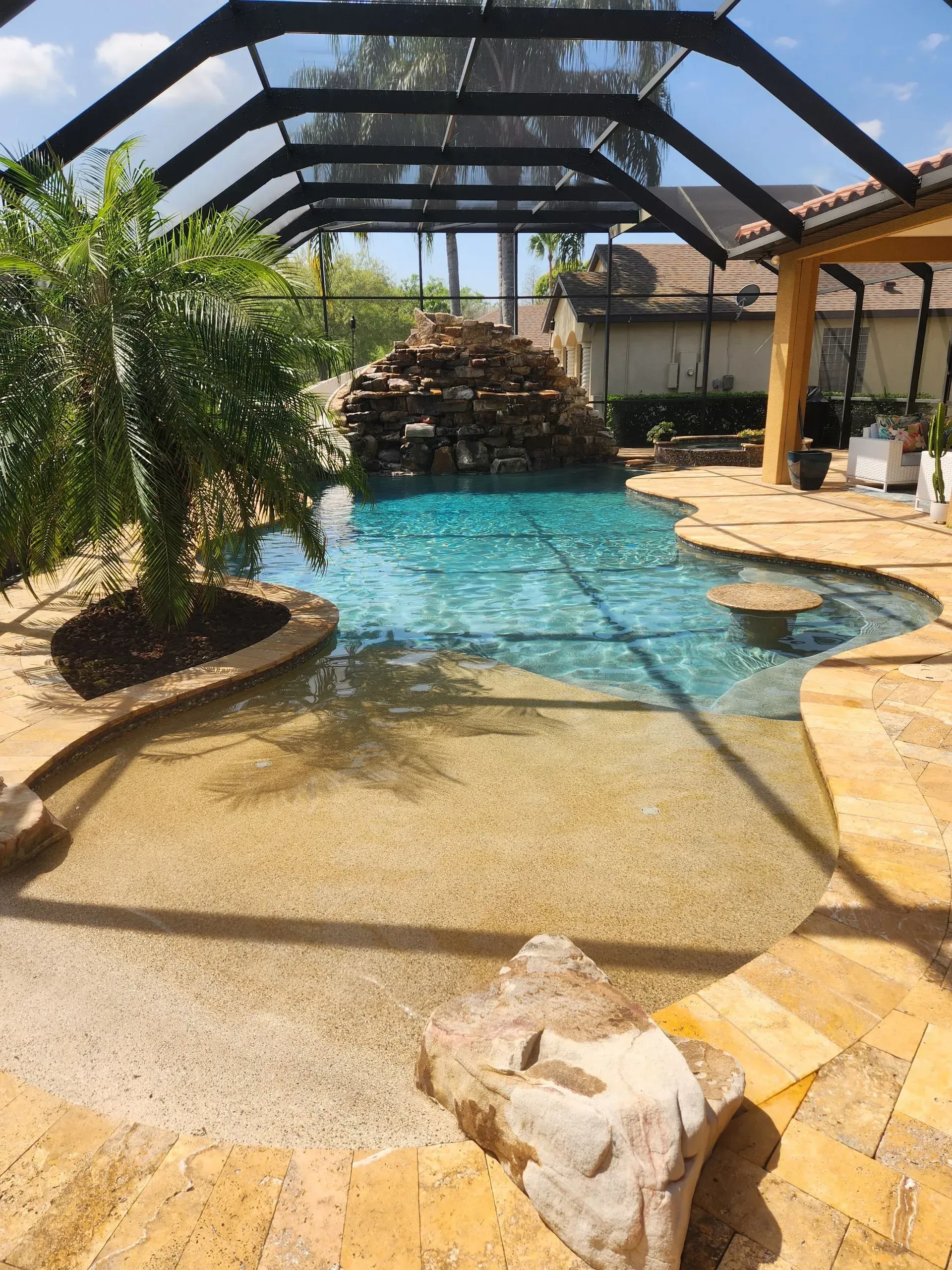 A large swimming pool with a screened in area in the backyard of a house.
