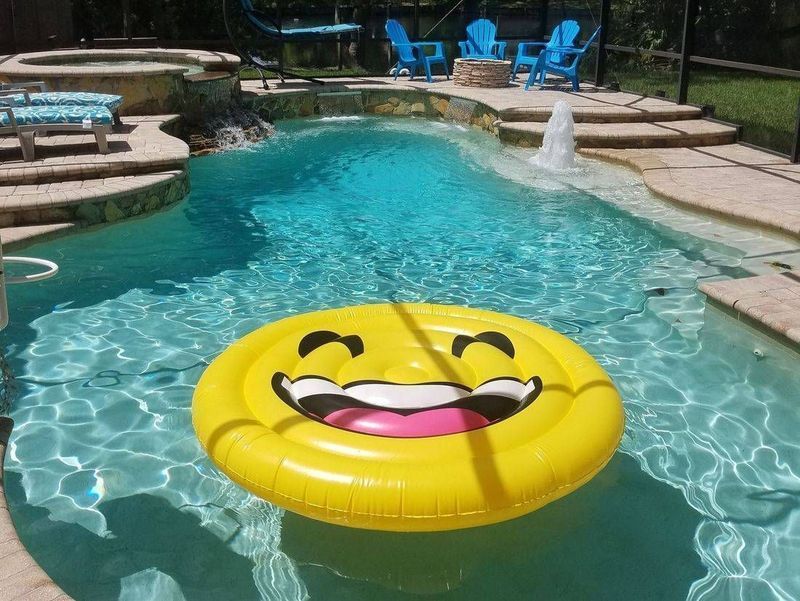 A yellow smiley face float is floating in a swimming pool.