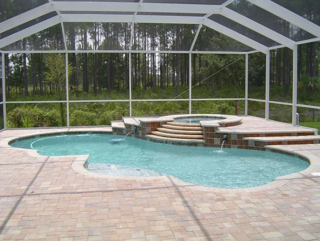 A screened in swimming pool with a hot tub underneath it