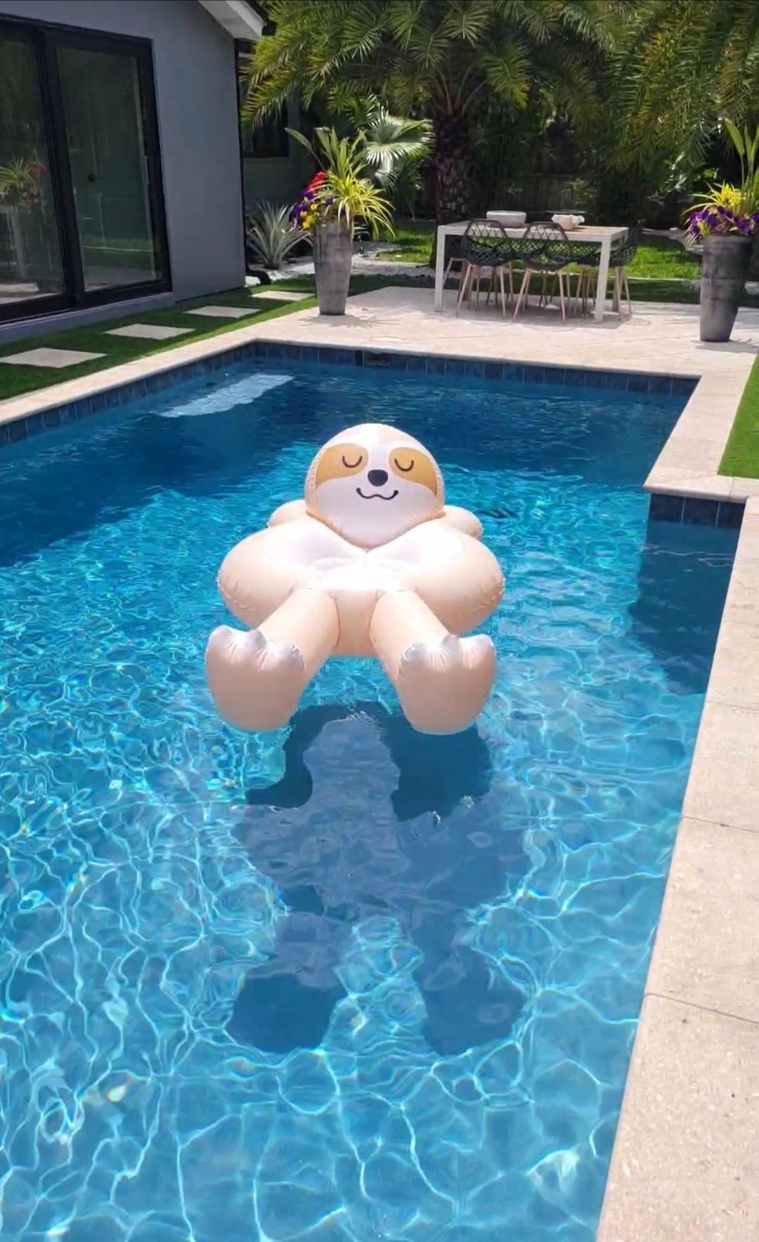 An inflatable sloth is floating on top of a swimming pool.