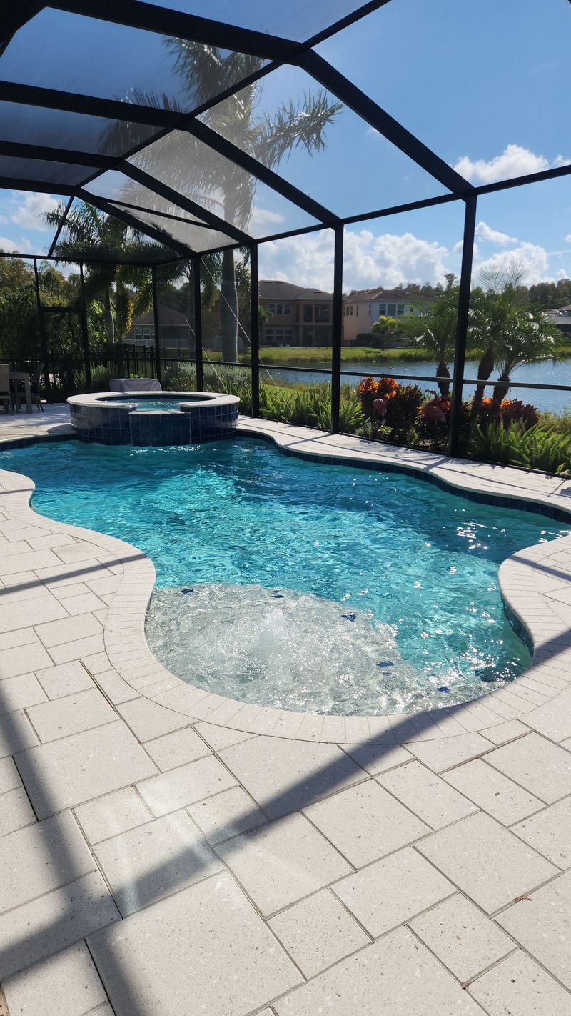 A large swimming pool is surrounded by a screened in area.