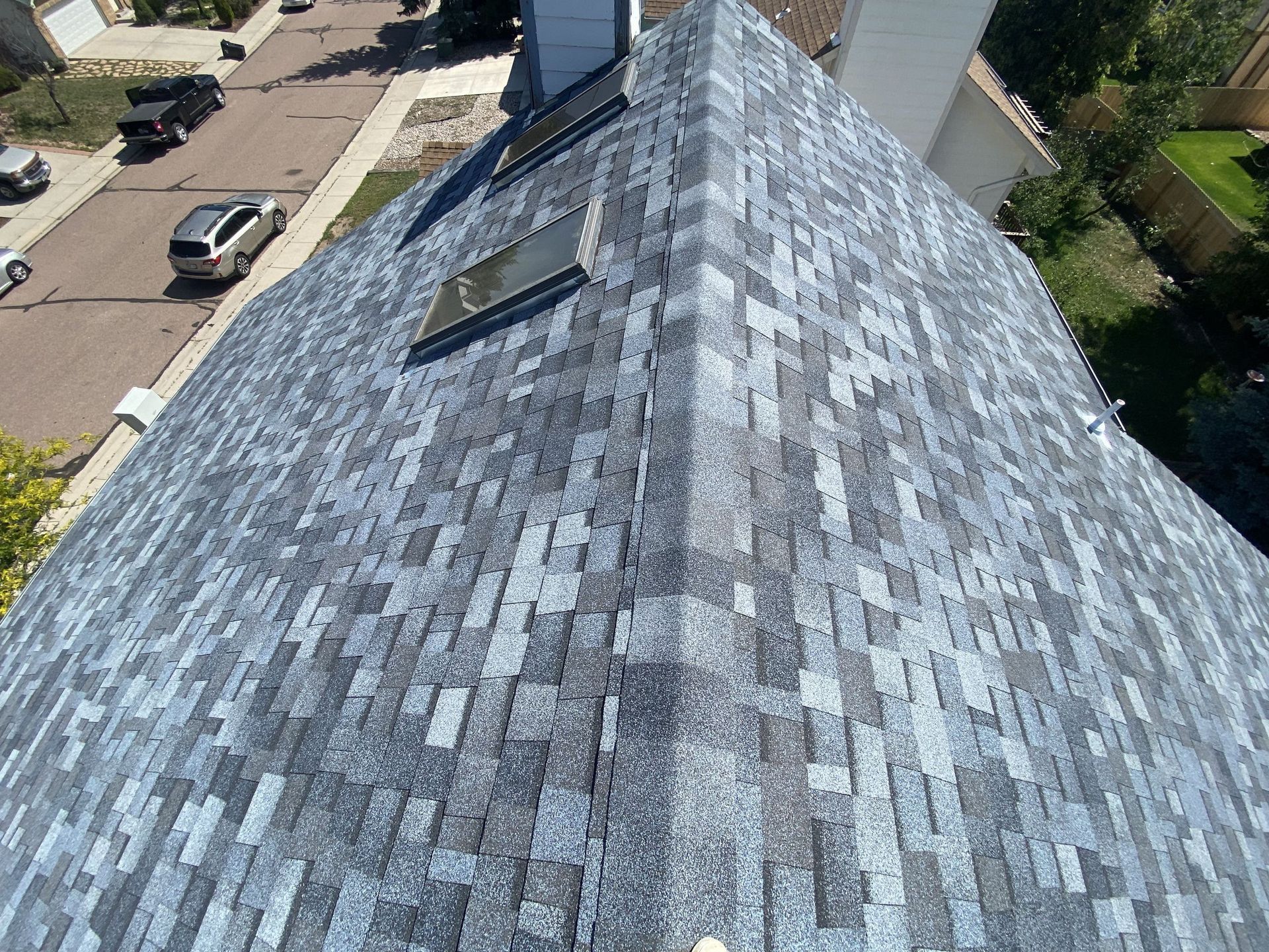 An aerial view of a roof with shingles and skylights.