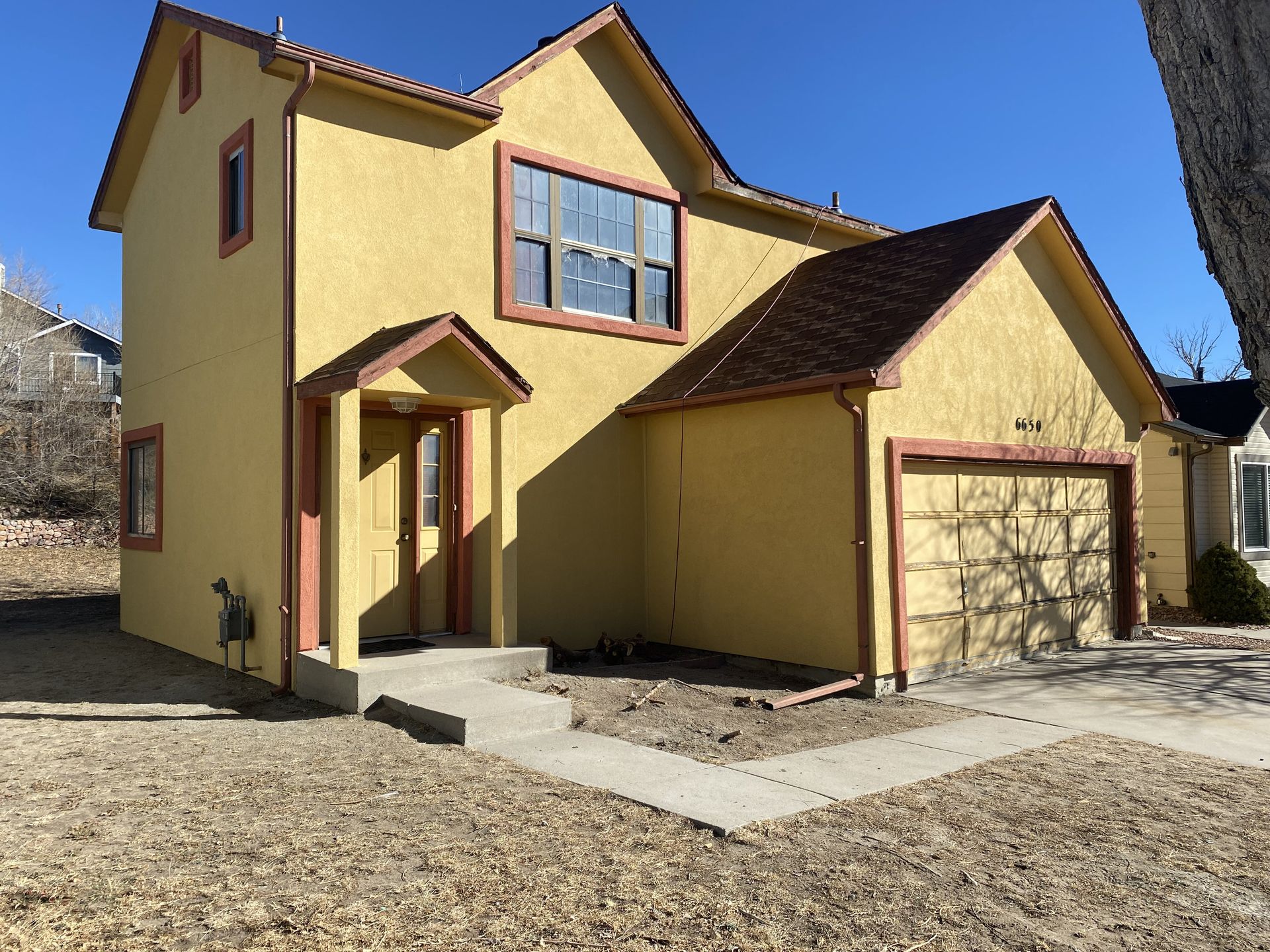 A yellow house with a red trim and a red roof