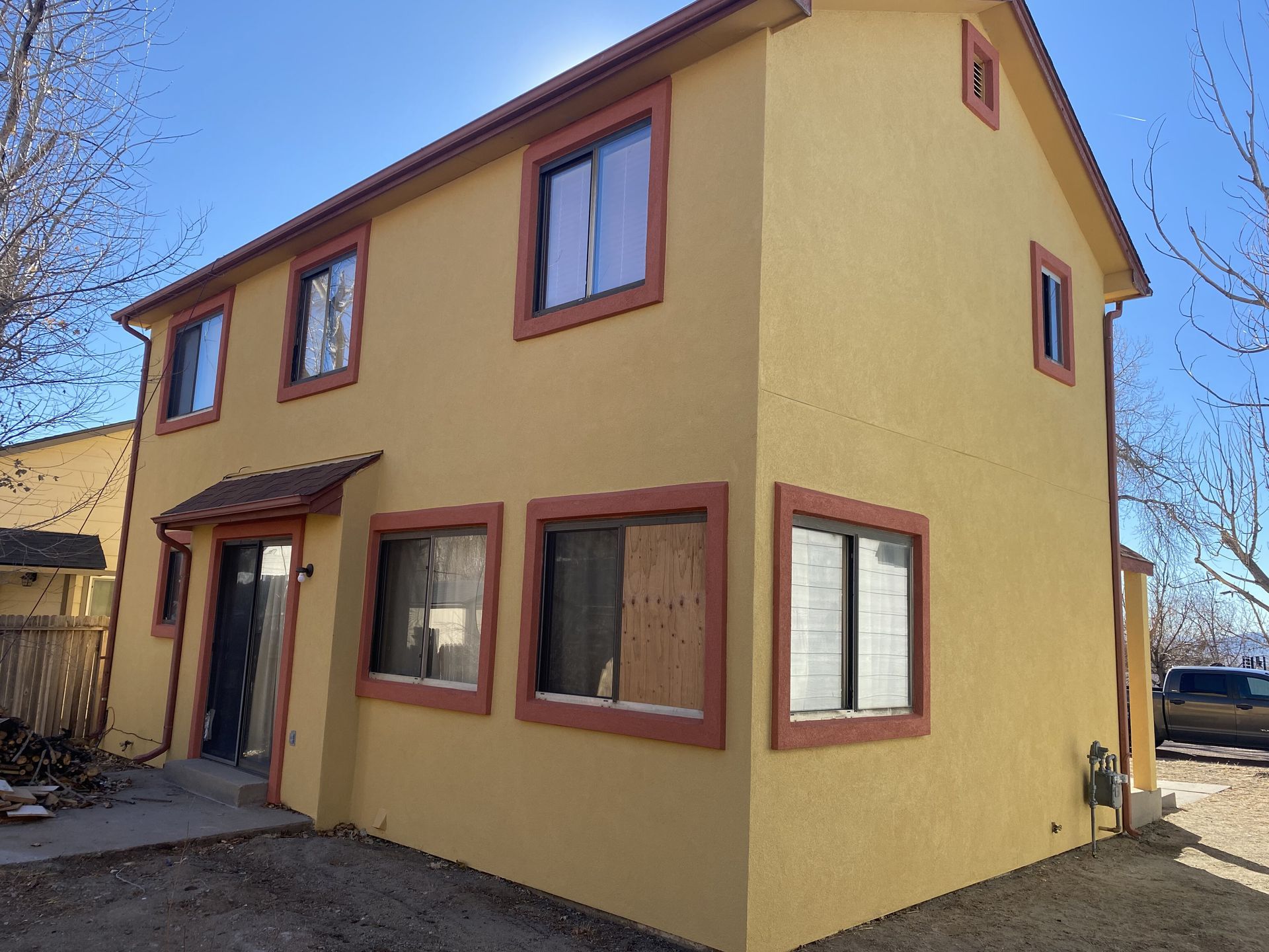 A yellow house with red trim and a lot of windows
