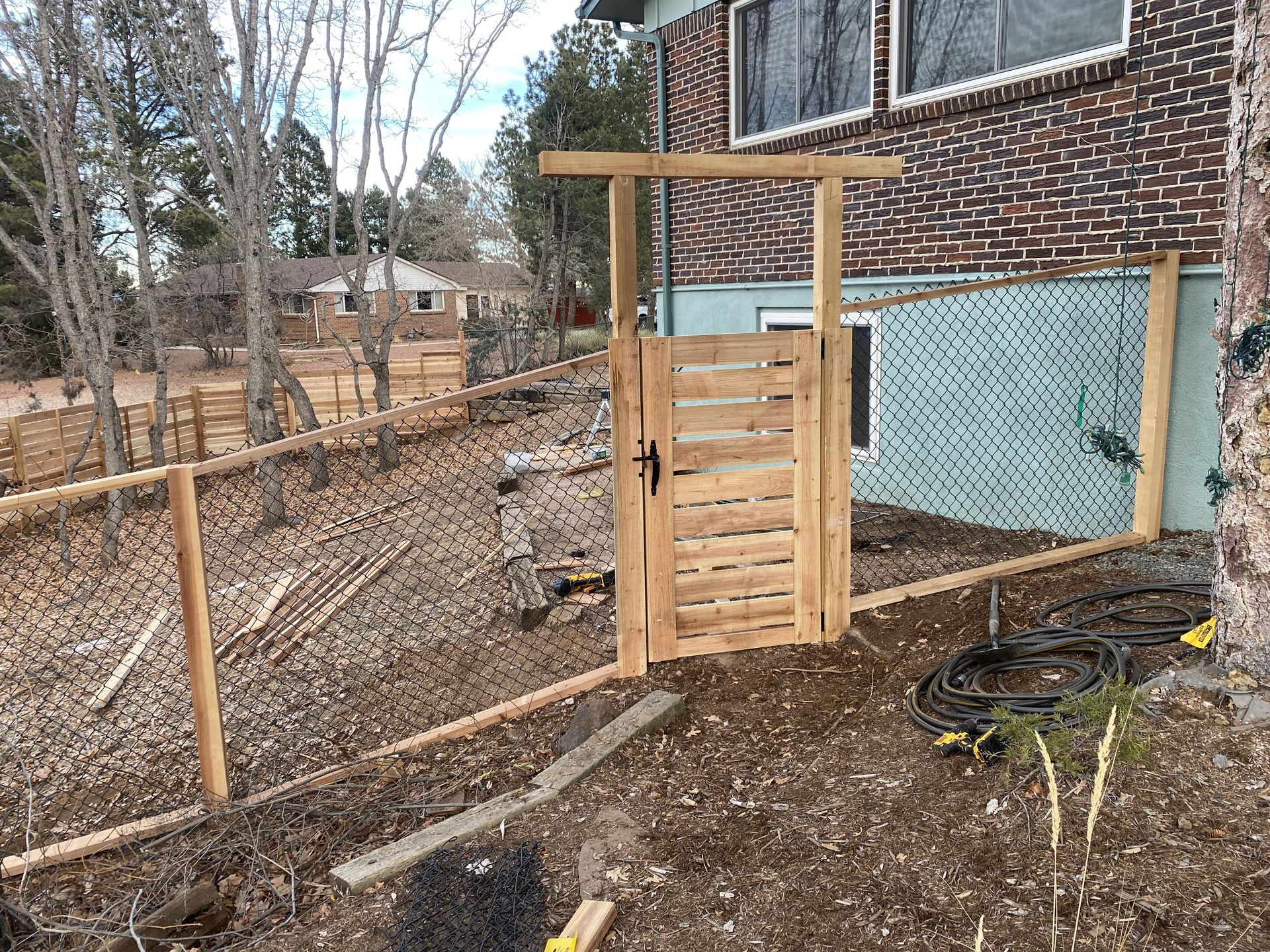 A wooden gate is sitting in front of a brick house.