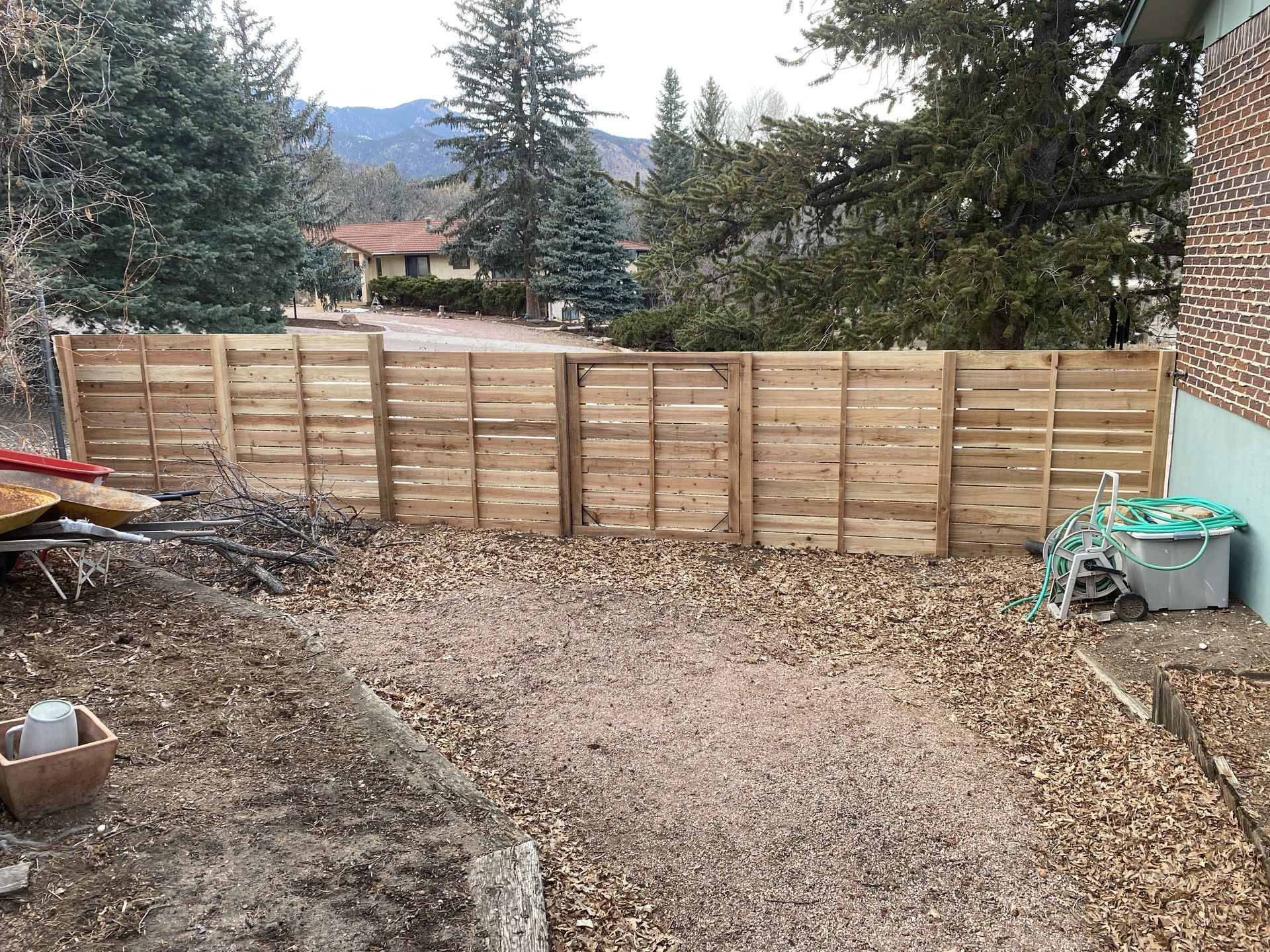A wooden fence is being built in the backyard of a house.