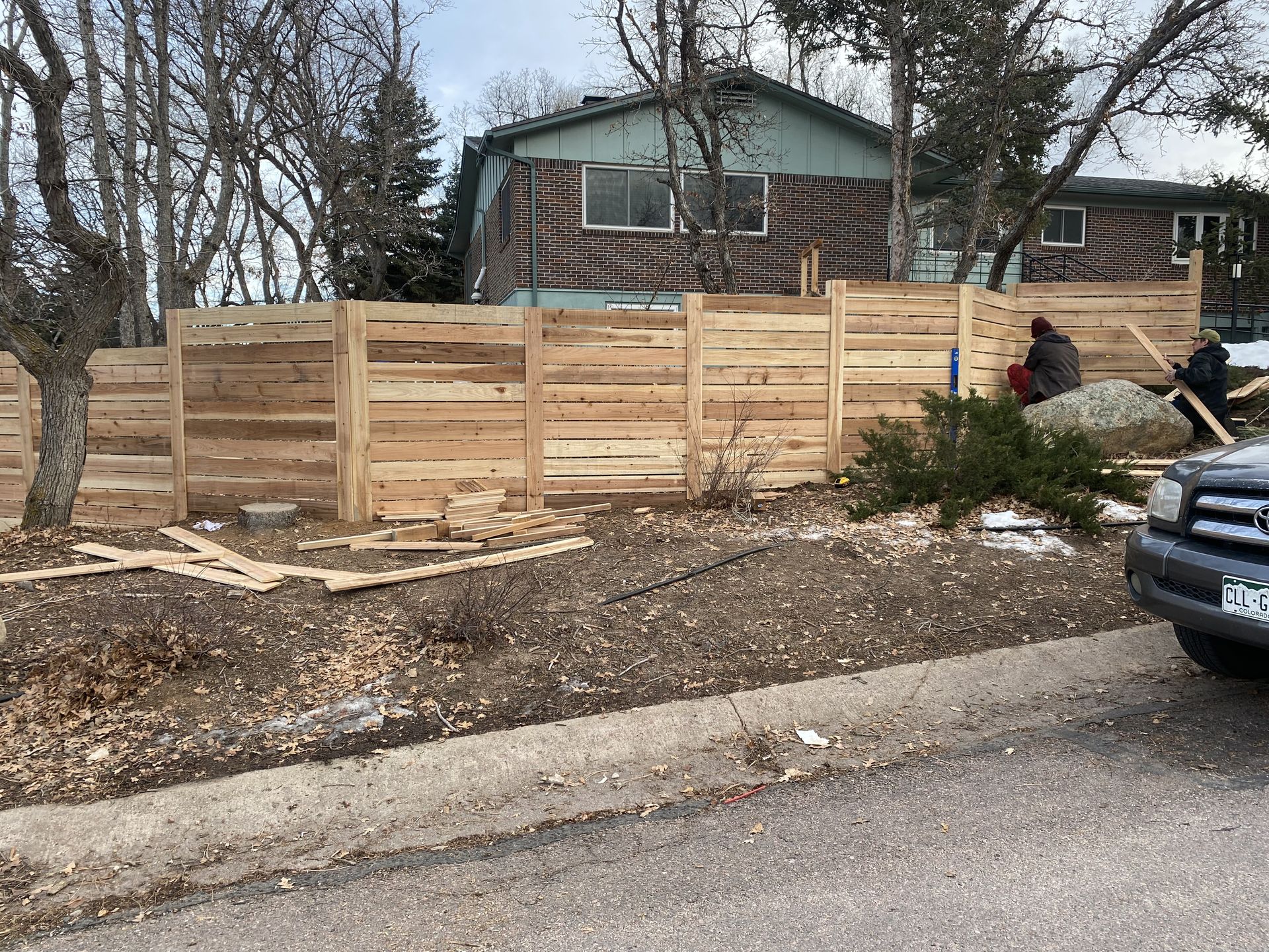 A wooden fence is being built in front of a house.