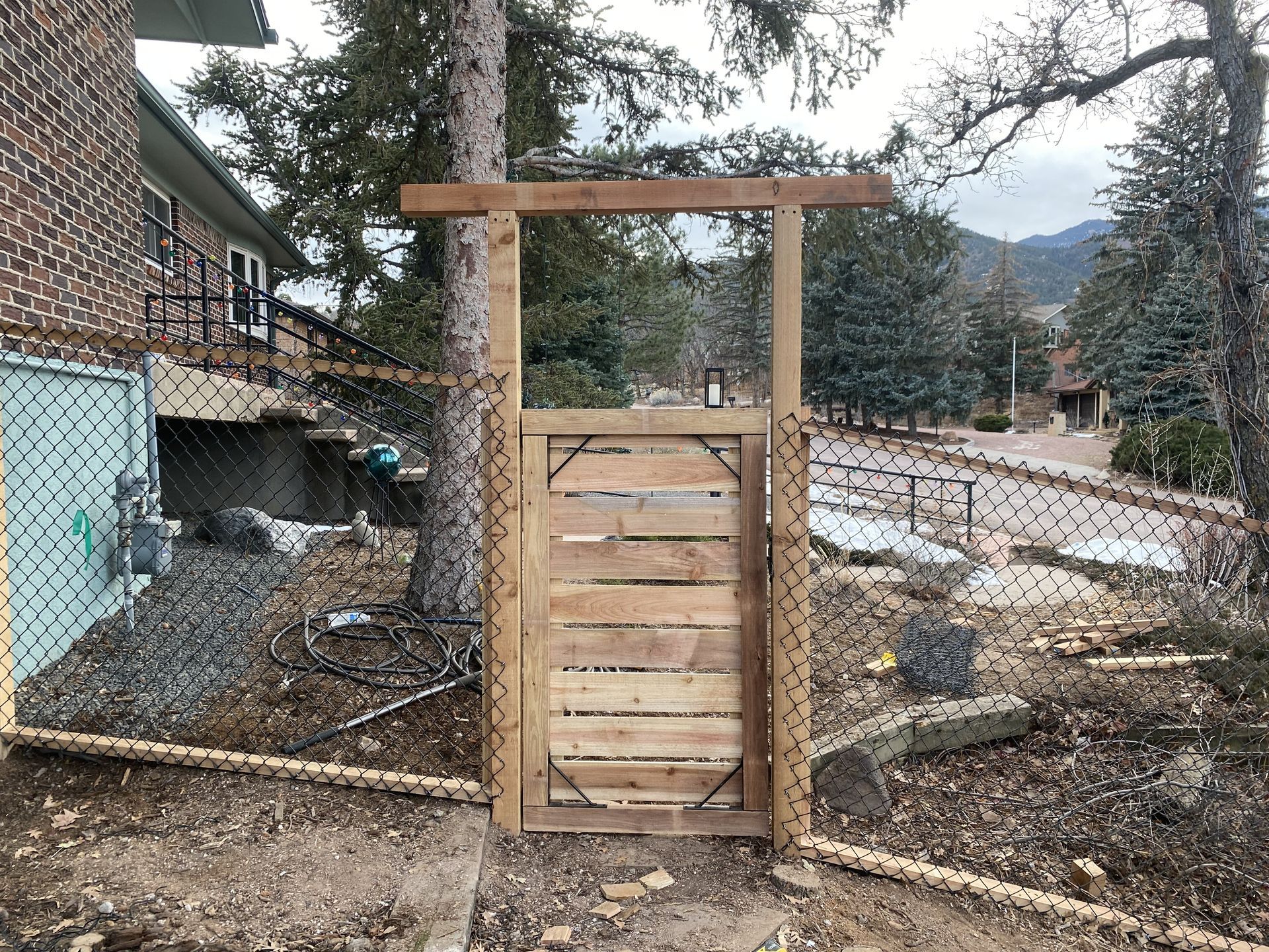 A wooden gate is sitting in front of a chain link fence.