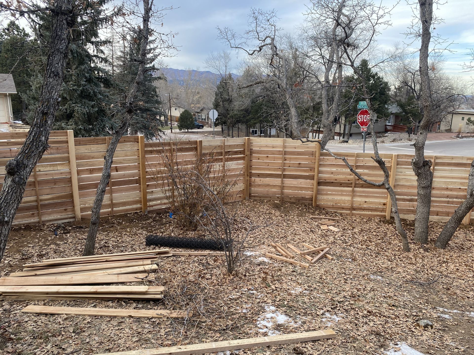 A wooden fence is being built in the backyard of a house.