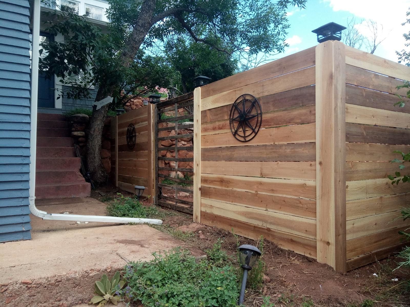 A wooden fence with a star on it is in front of a house.