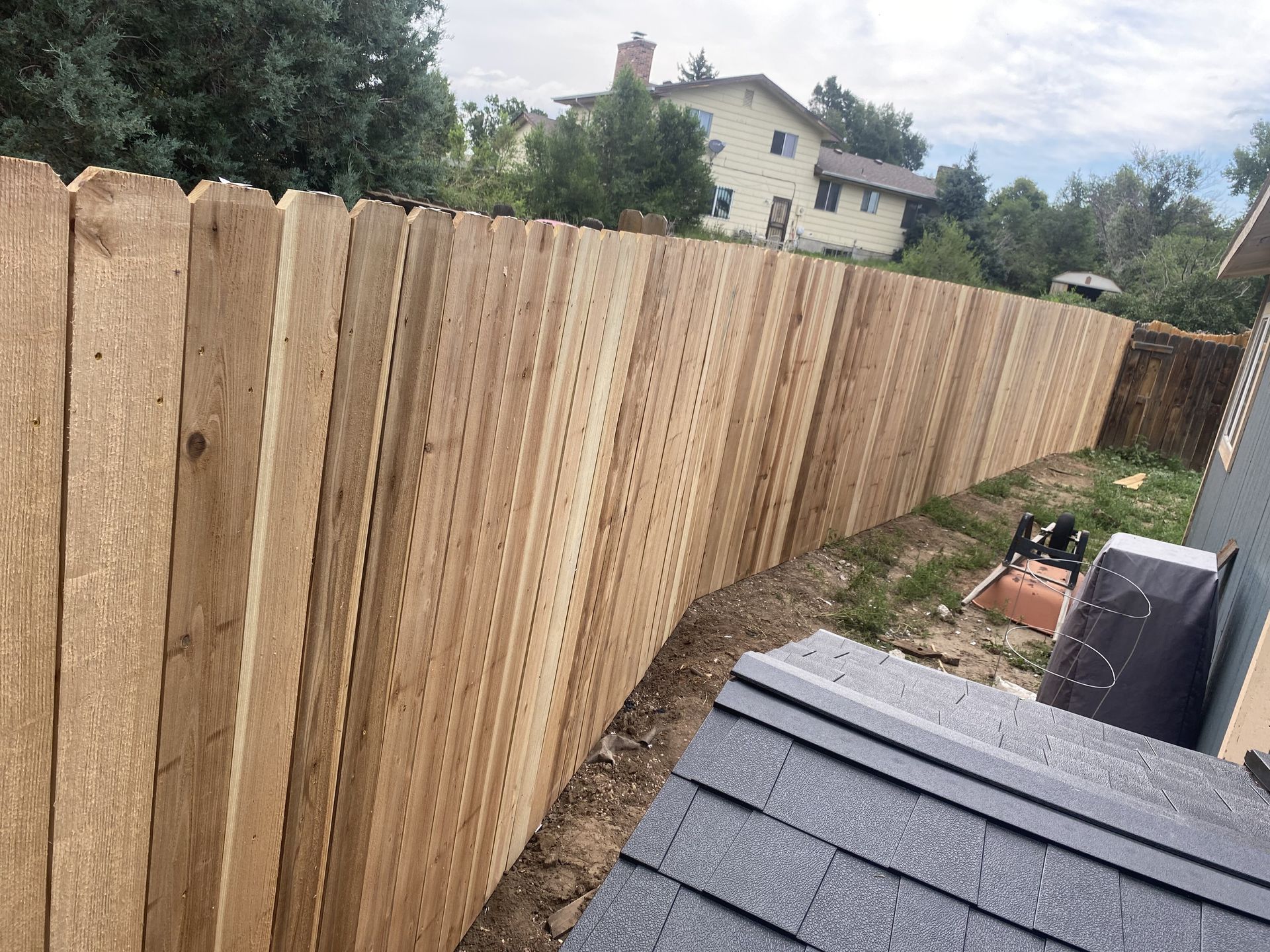 A wooden fence is being built in the backyard of a house.