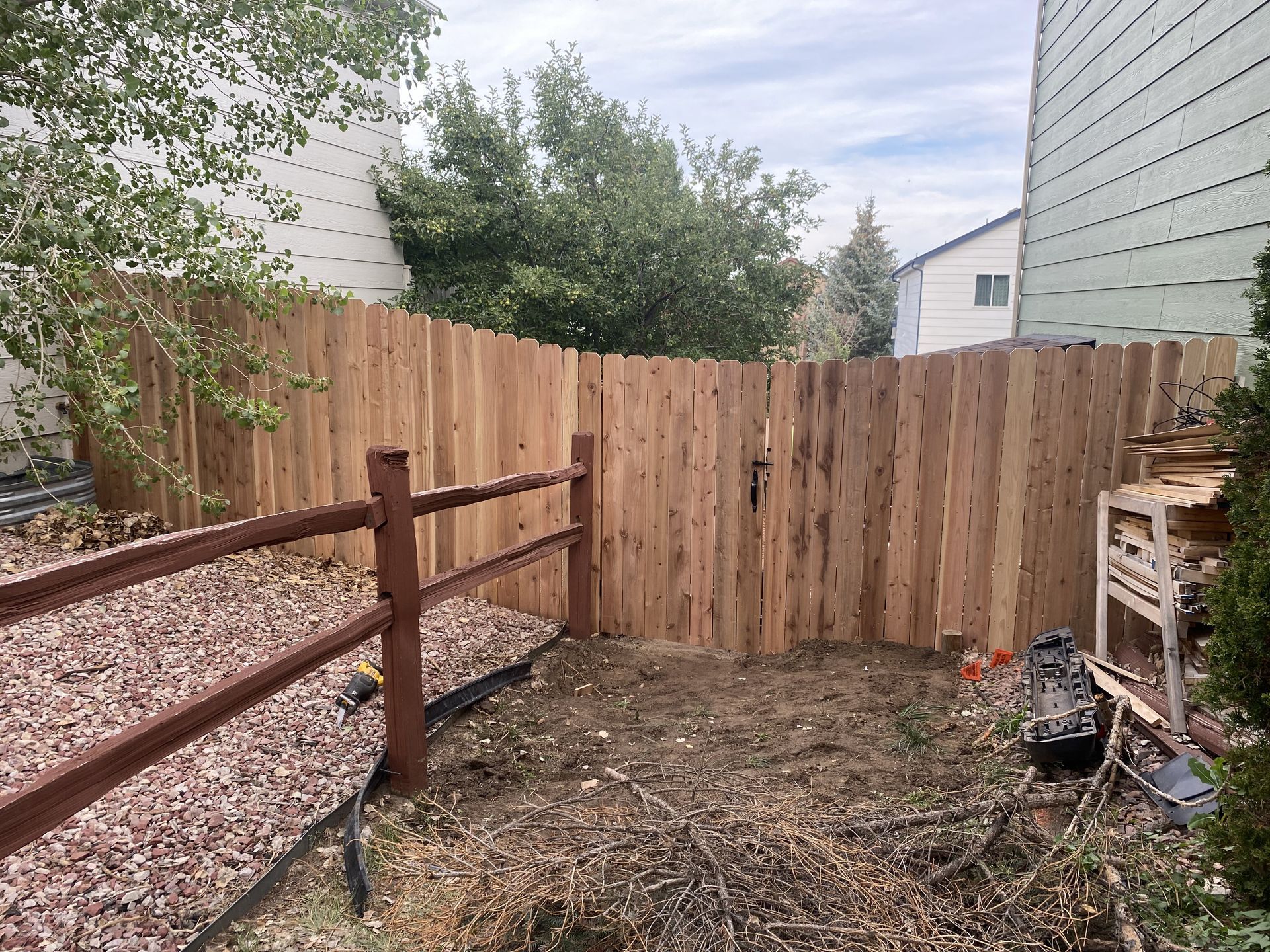 A wooden fence is in the backyard of a house.
