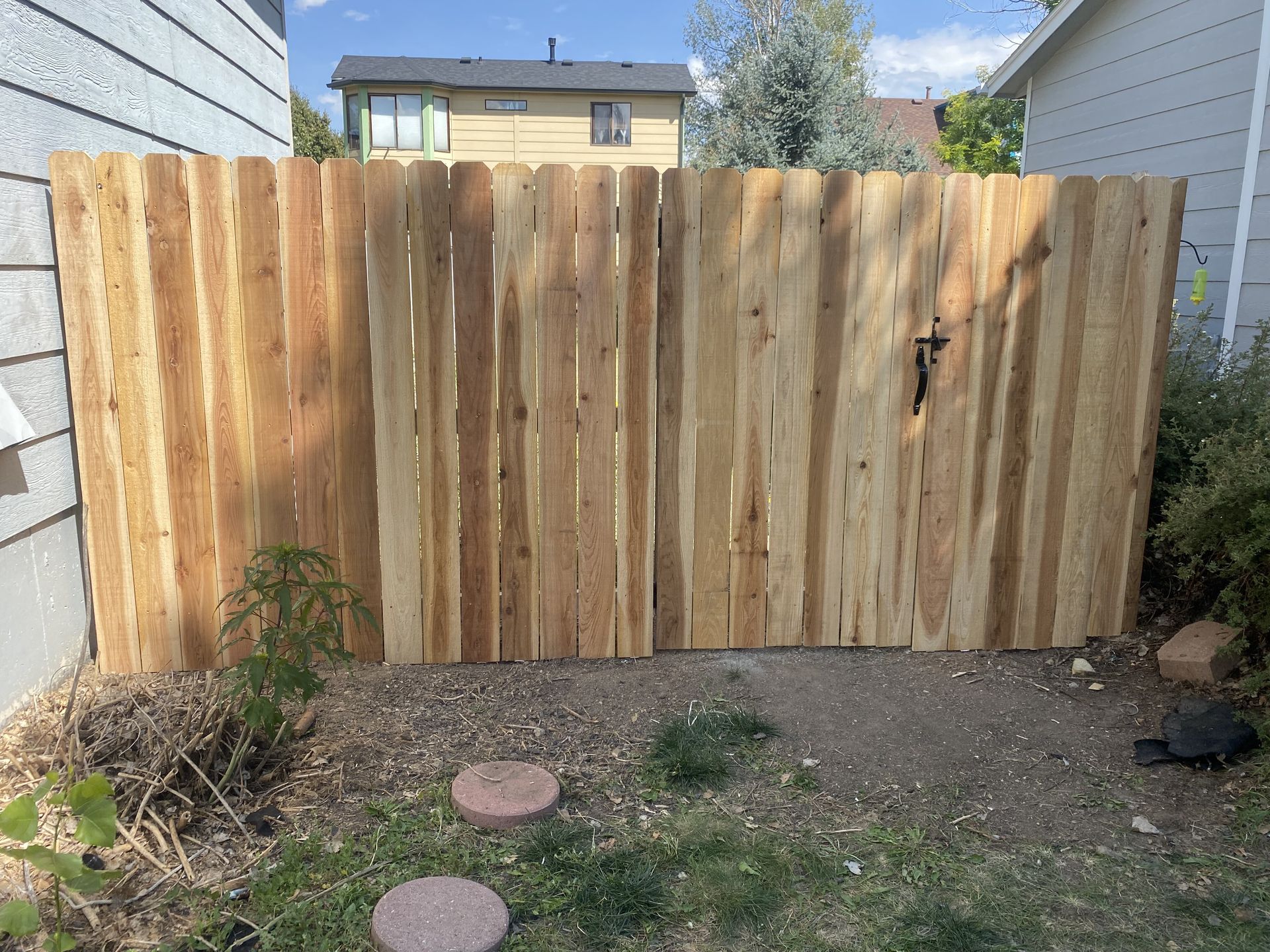 A wooden fence with a gate in the backyard of a house.