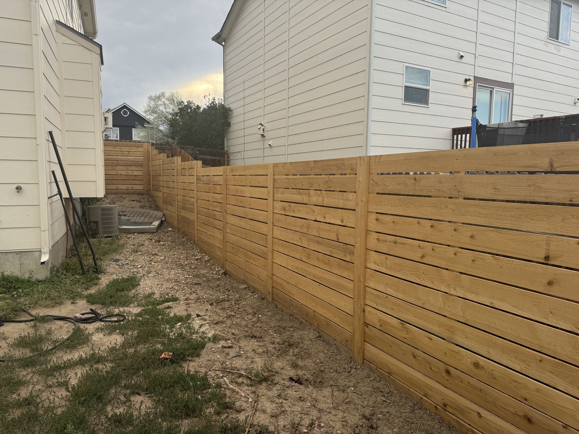 A wooden fence is in the backyard of a house.
