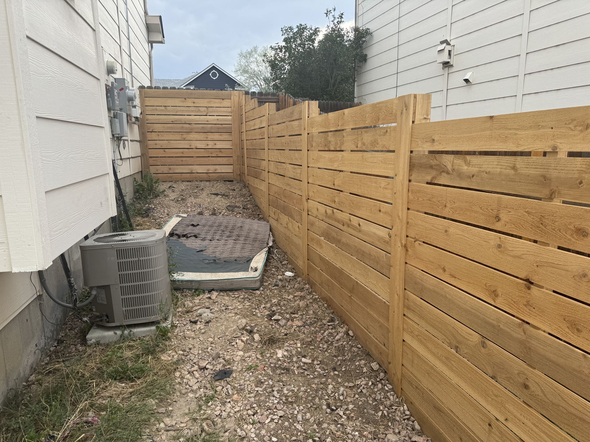 A wooden fence is in the backyard of a house.