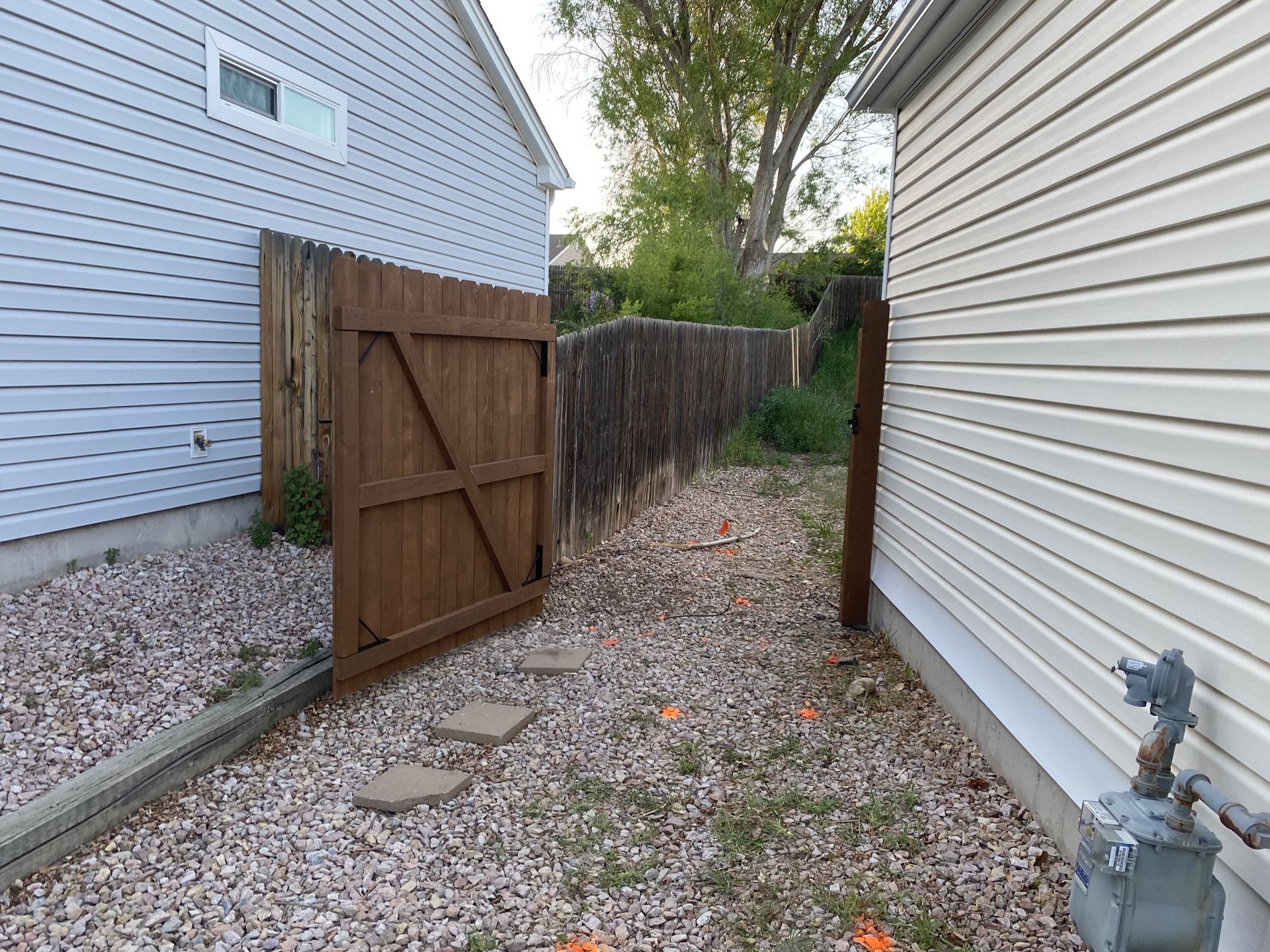 There is a wooden gate in the backyard between two houses.
