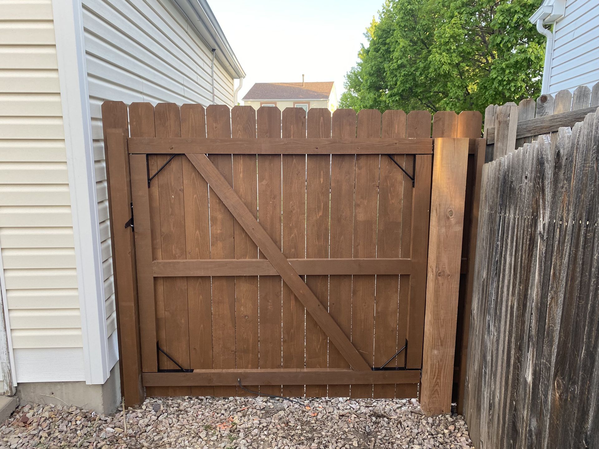A wooden fence with a gate in the backyard of a house.
