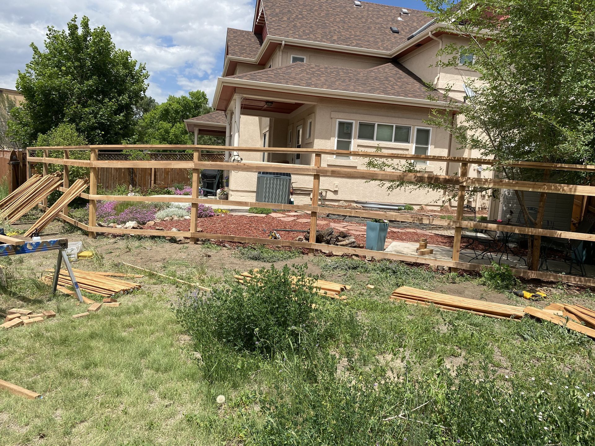 A wooden fence is being built in the backyard of a house.