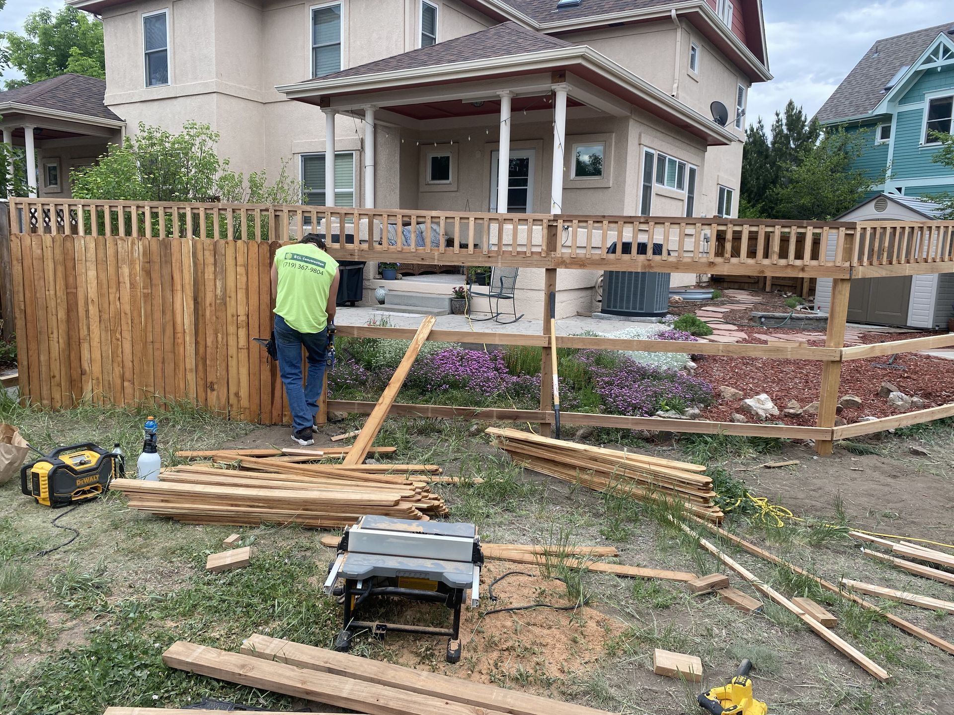 A man is working on a wooden fence in front of a house.