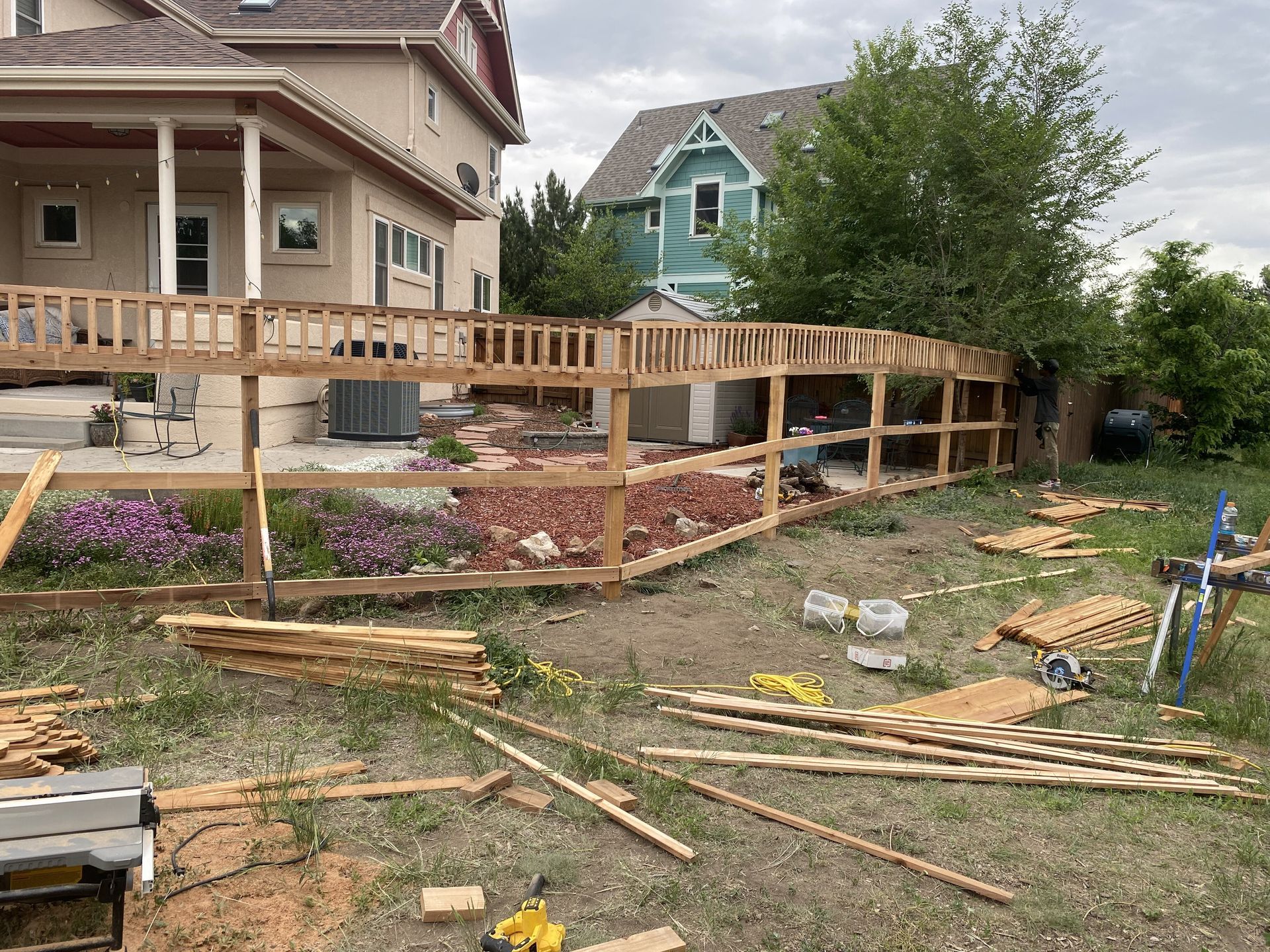A wooden fence is being built in the backyard of a house.