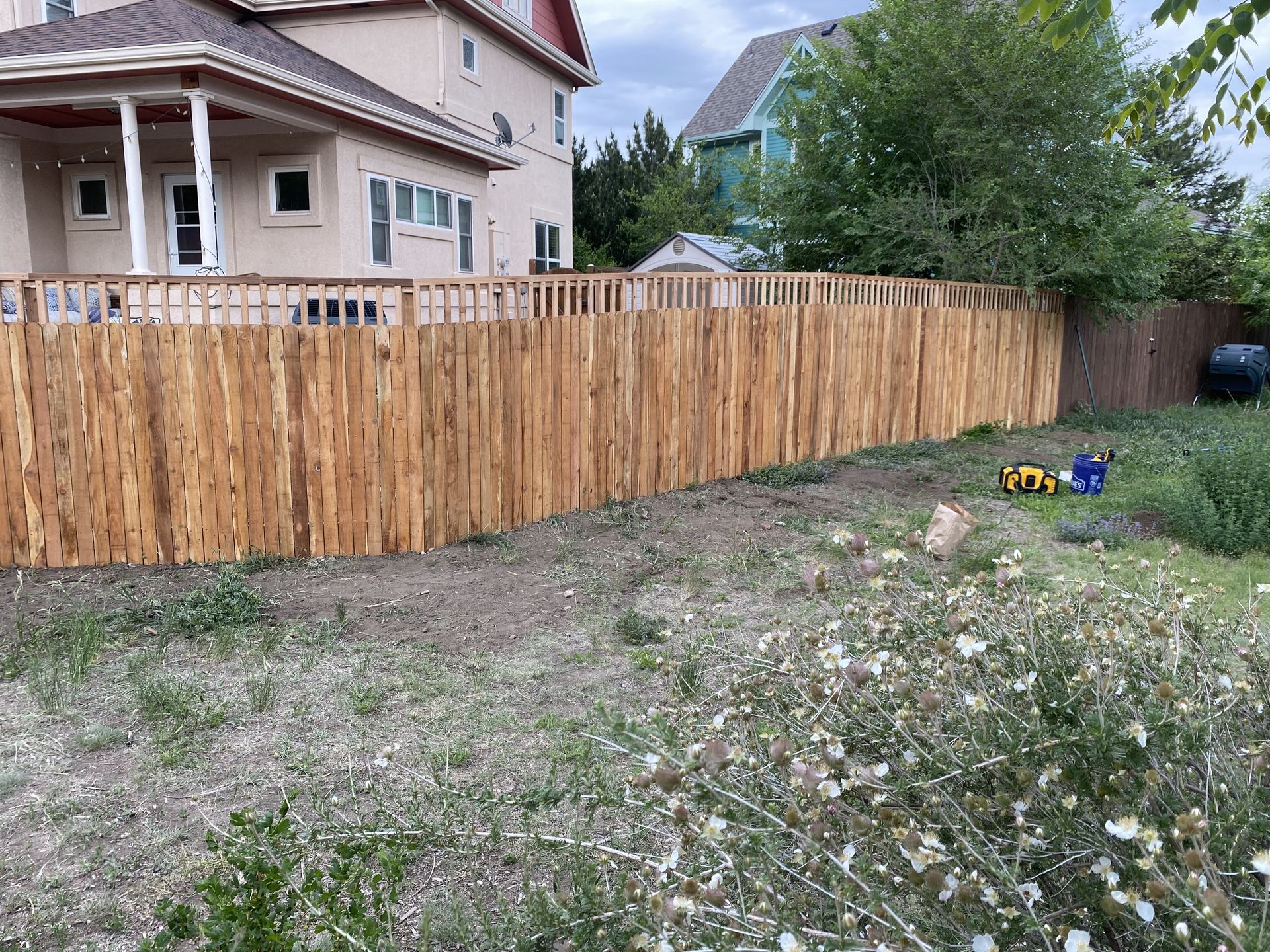 A wooden fence is in the backyard of a house.