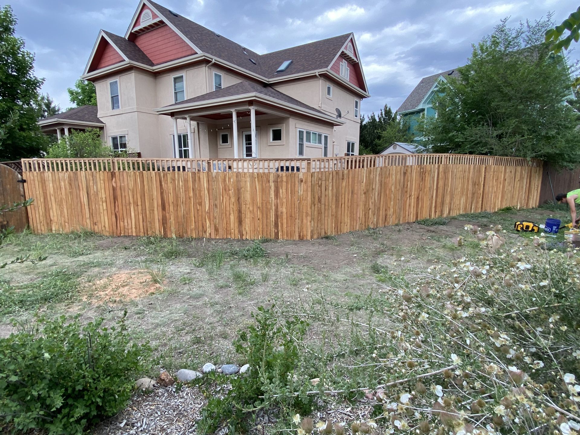 A wooden fence is being built in front of a large house.