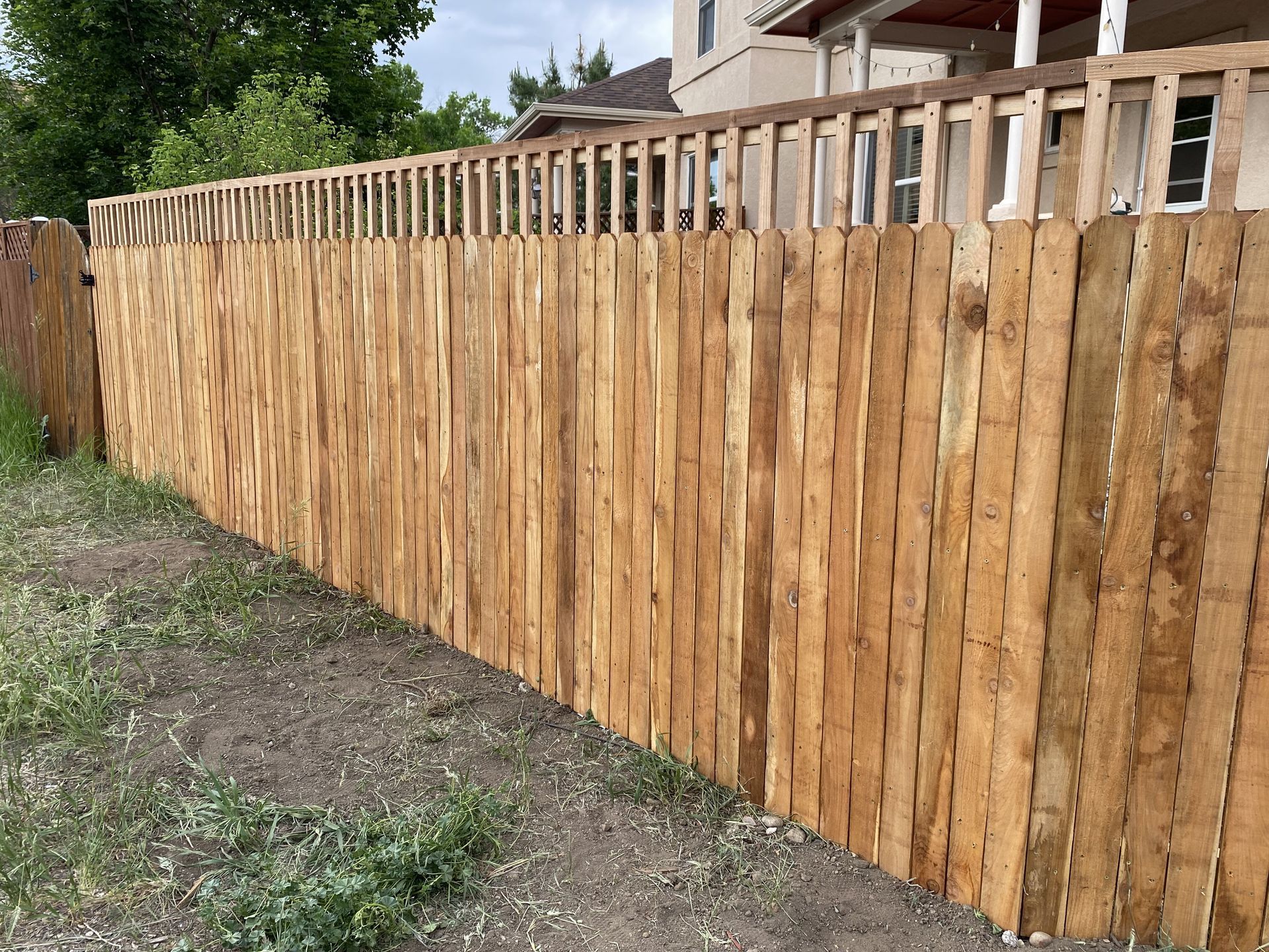A long wooden fence with a house in the background.