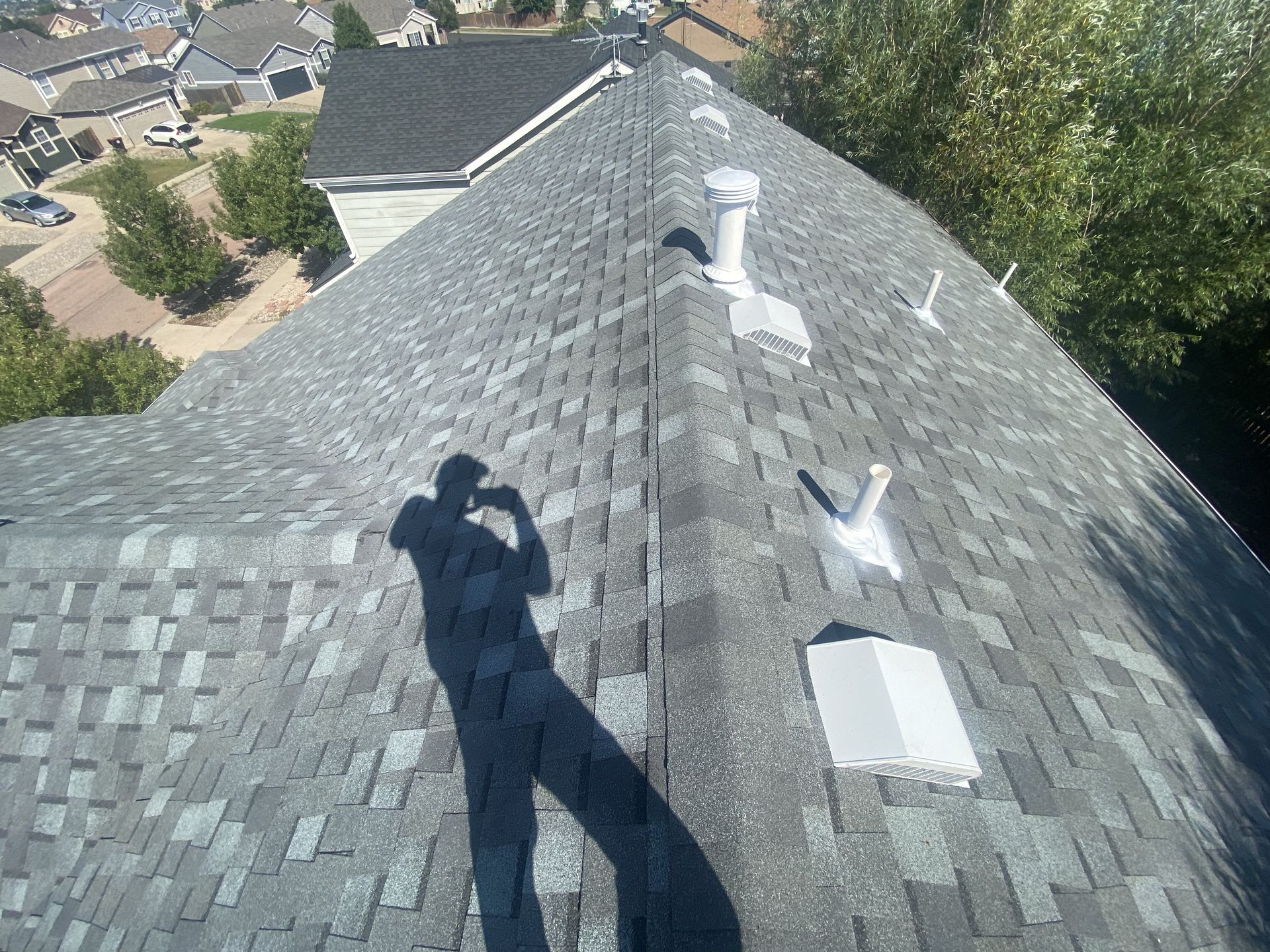 A shadow of a person is cast on the roof of a house