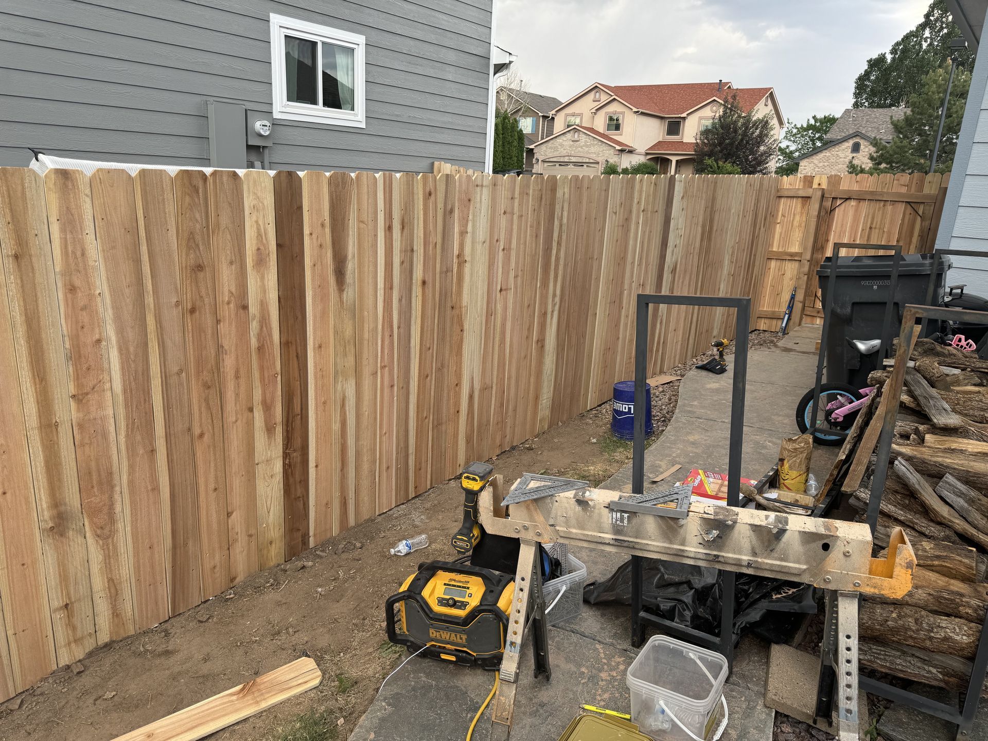 A wooden fence is being built in the backyard of a house.