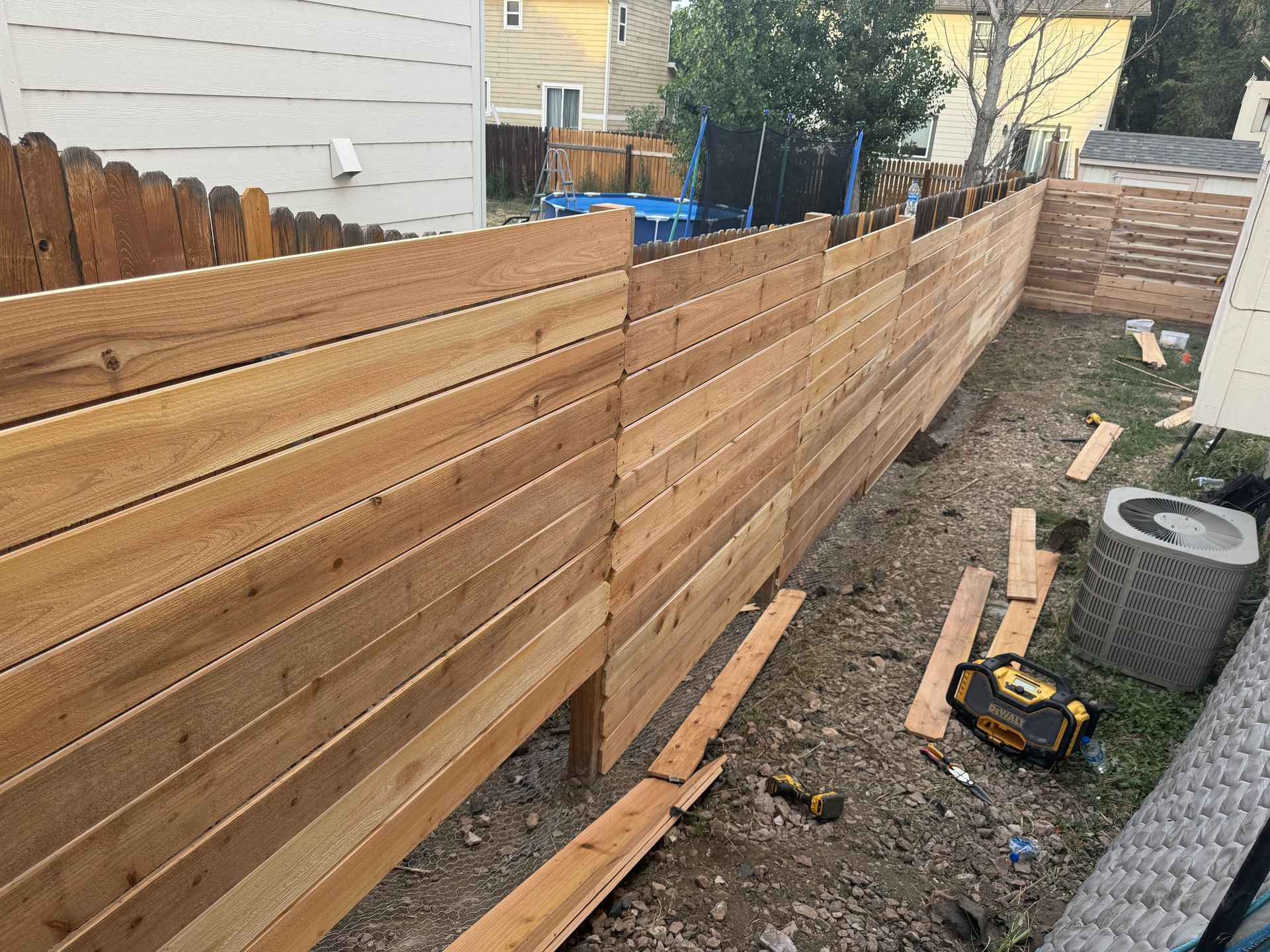 A wooden fence is being built in a backyard.