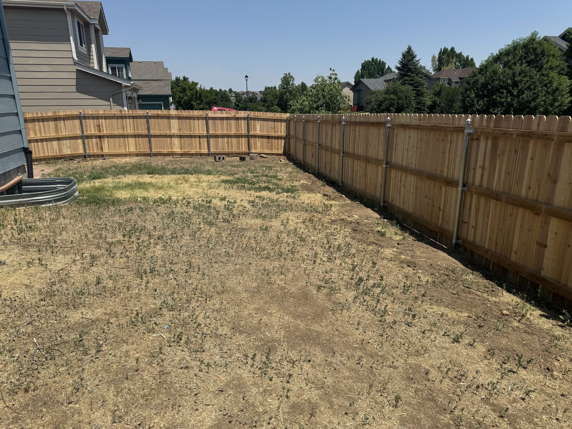 A backyard with a wooden fence and a lot of grass
