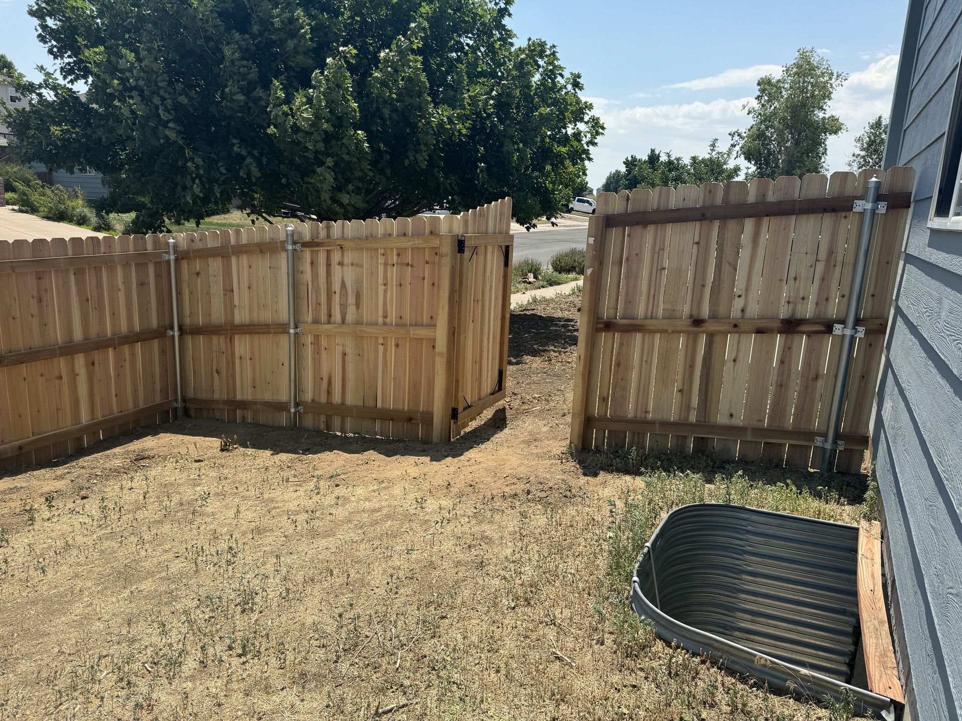 A wooden fence is in the backyard of a house.
