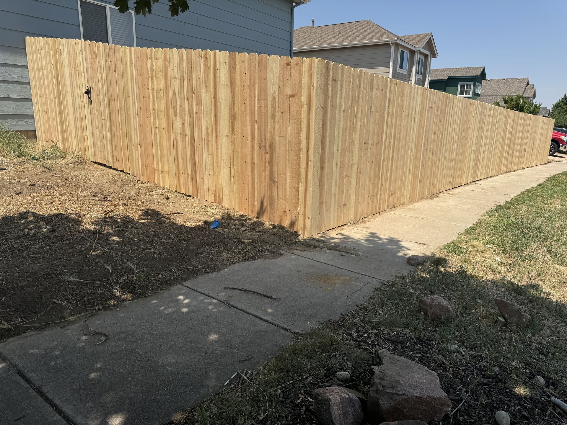 A wooden fence along a sidewalk next to a house.